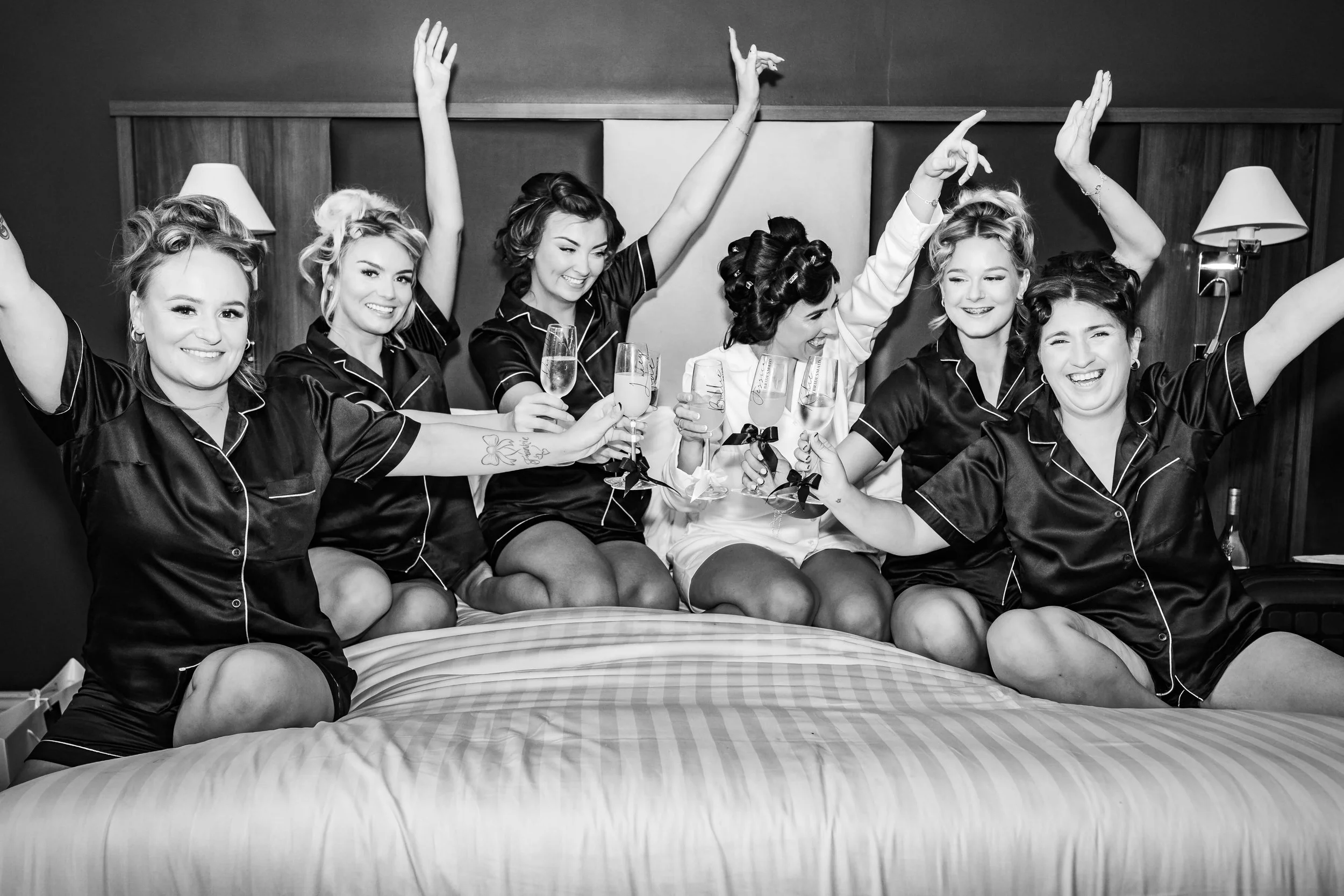 Bride and her bridal party laughing together whilst drinking champagne 