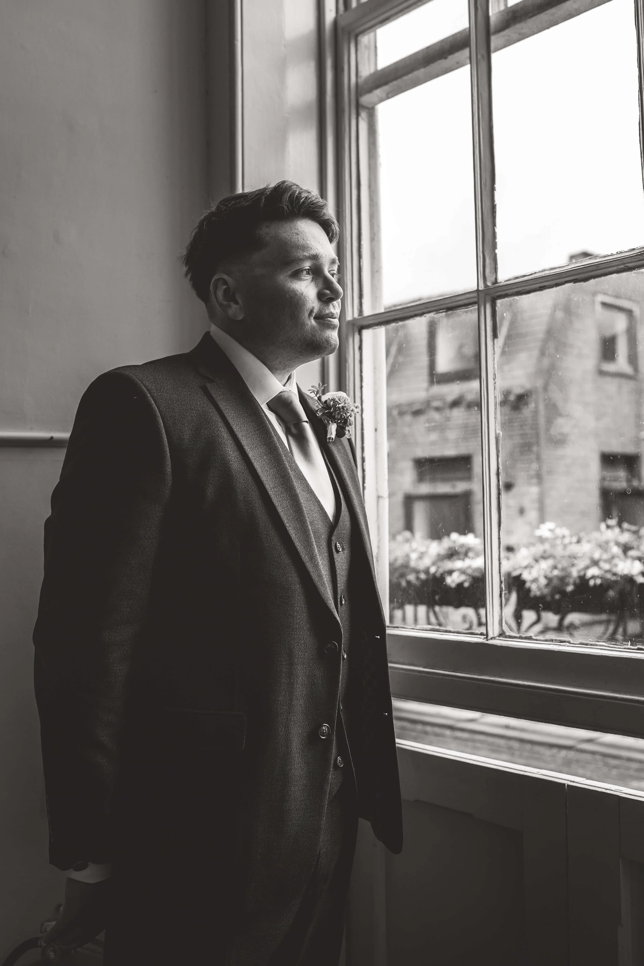 groom gazing out of sash windows in courthouse ceremony room