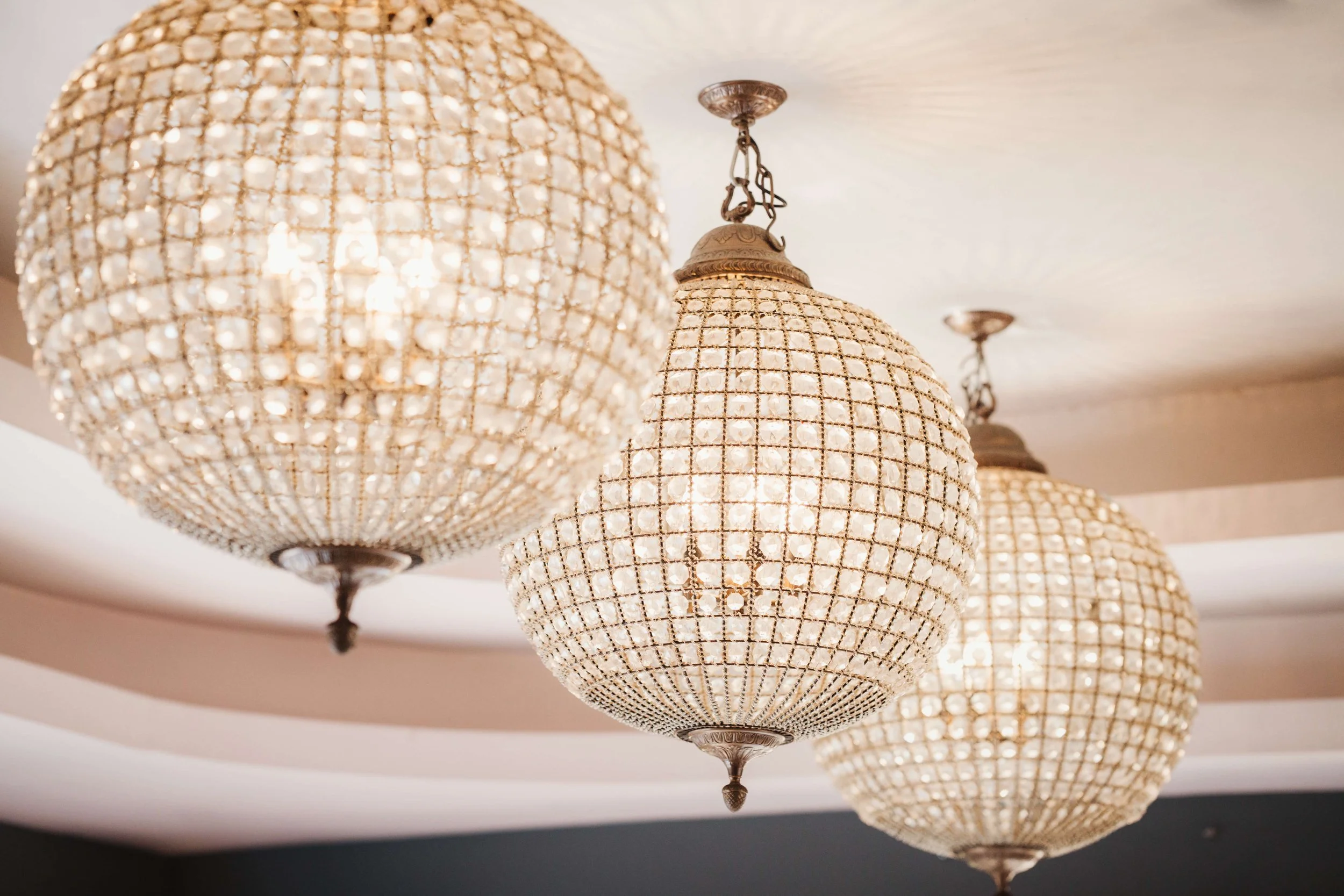 Three vintage-style chandeliers with glass beads hanging from the ceiling.
