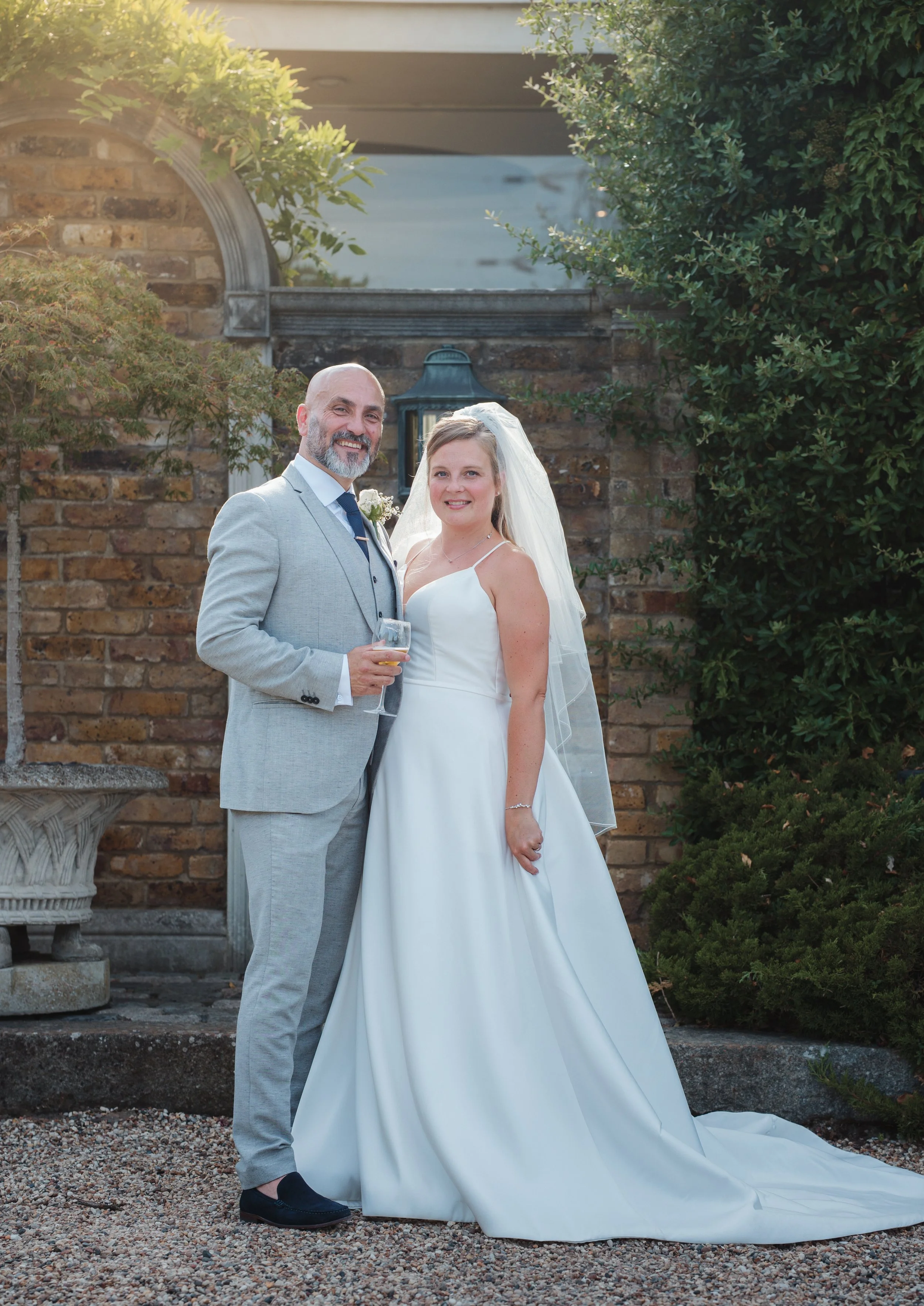 Wedding couple posing with champagne in the garden of friern manor 