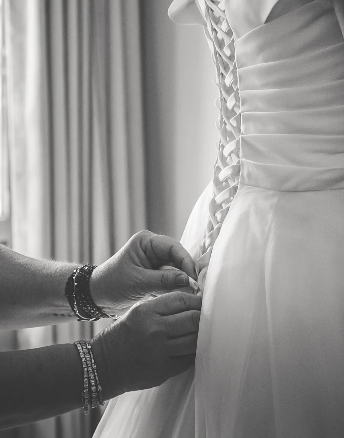 Person fixing the back seam of a wedding dress.