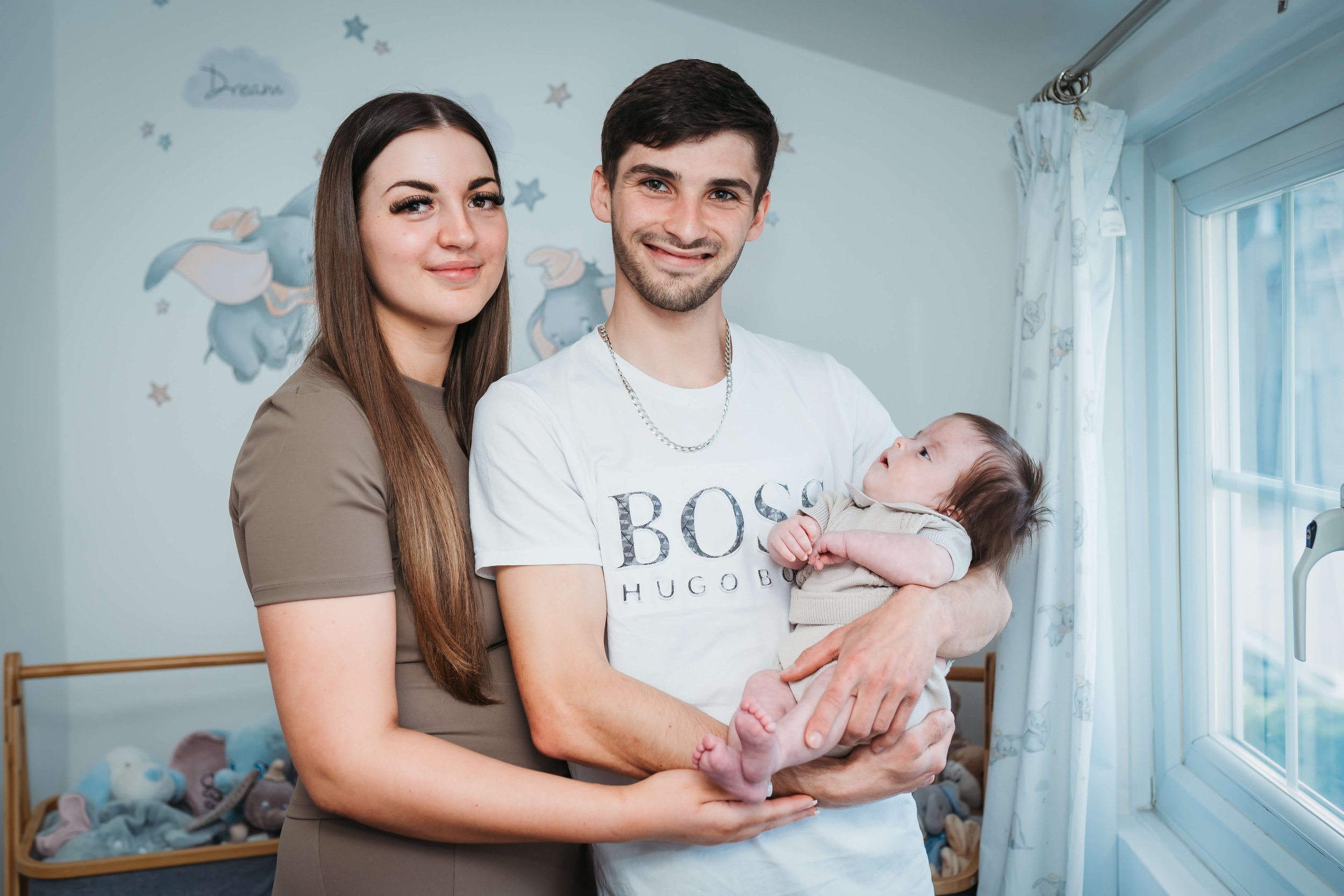 mum and dad holding baby in his nursery 