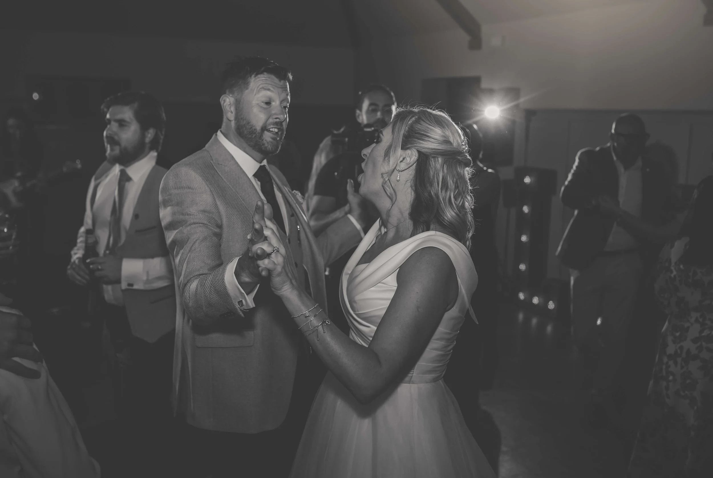 A couple dancing at a wedding reception with guests in the background.