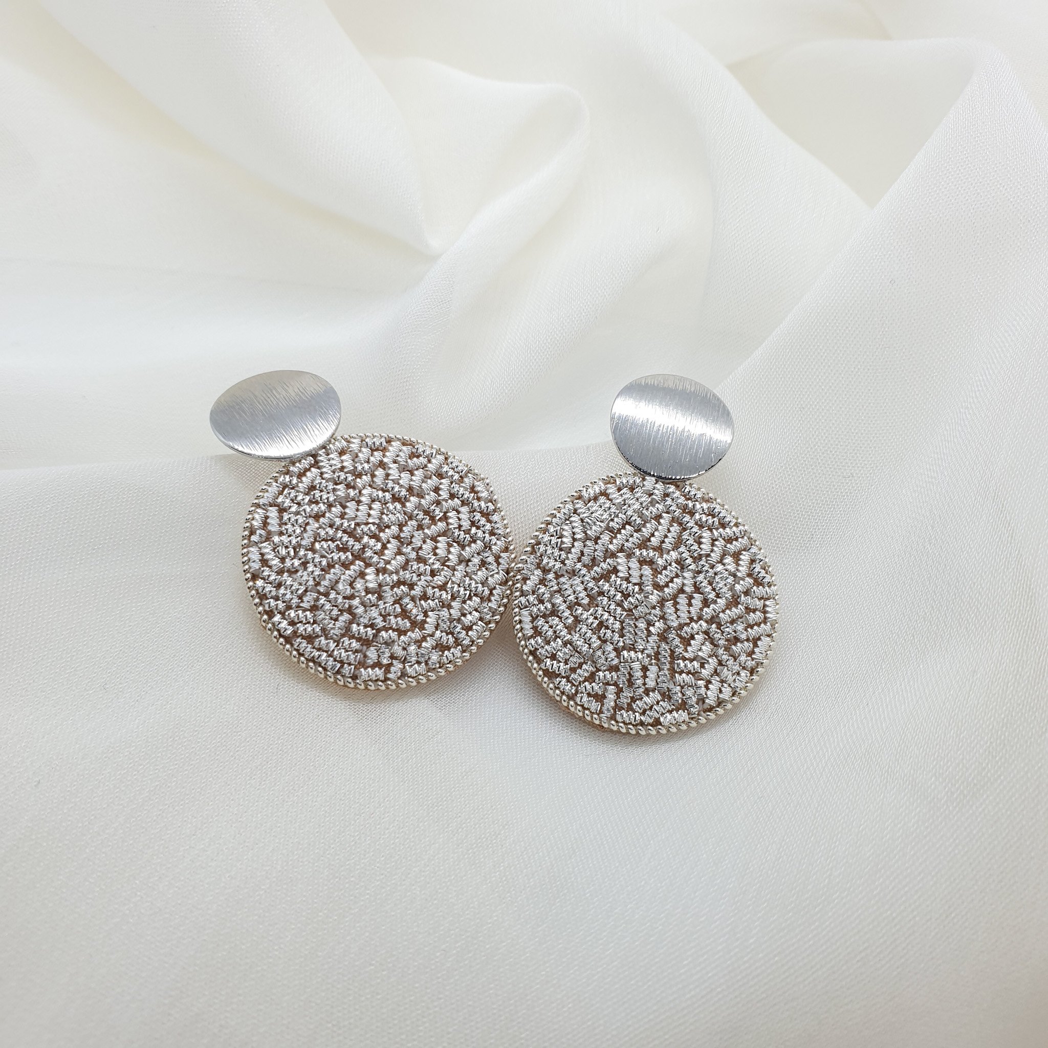 Simple circle earrings filled with sparkly silver hand embroidery.