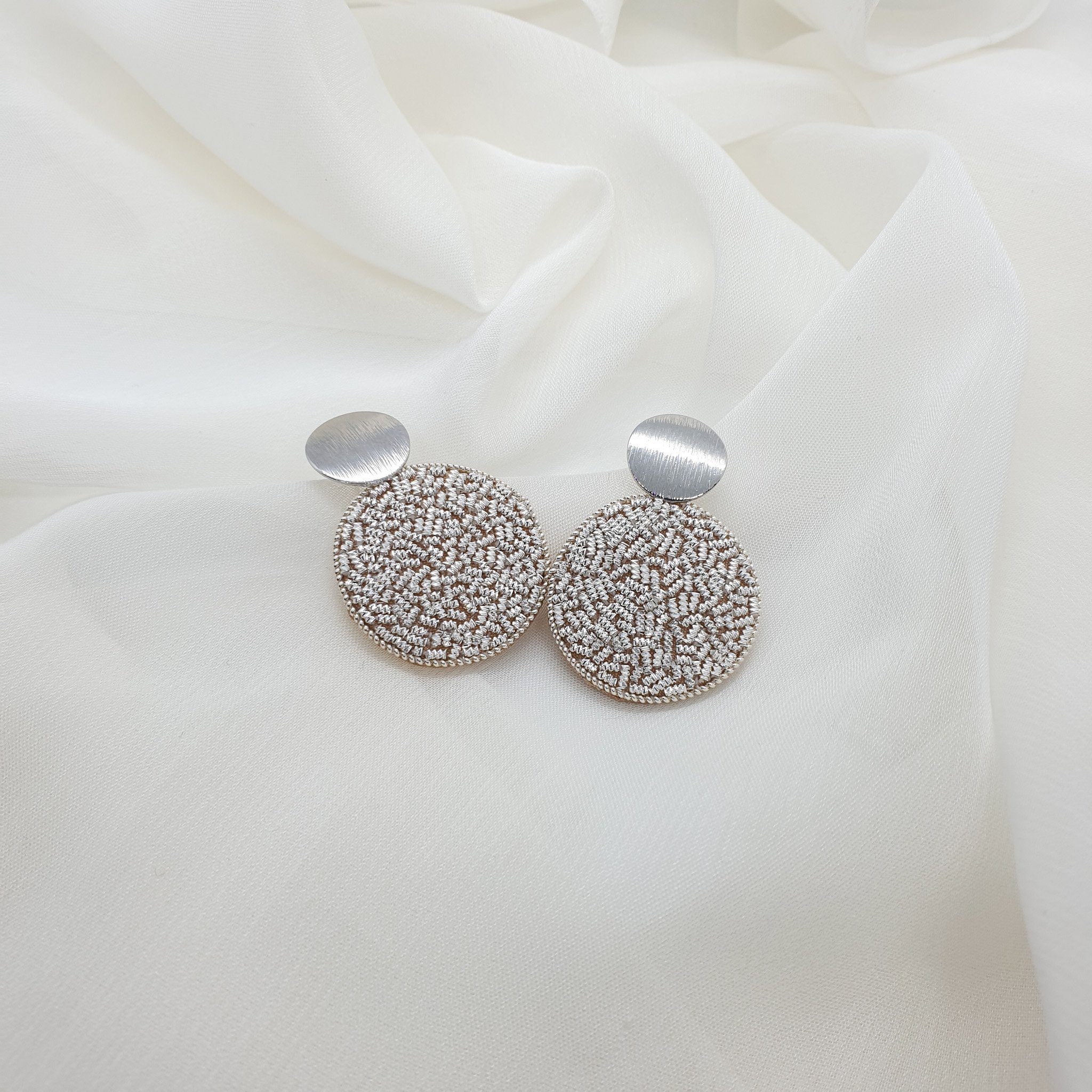 Simple circle earrings filled with sparkly silver hand embroidery.
