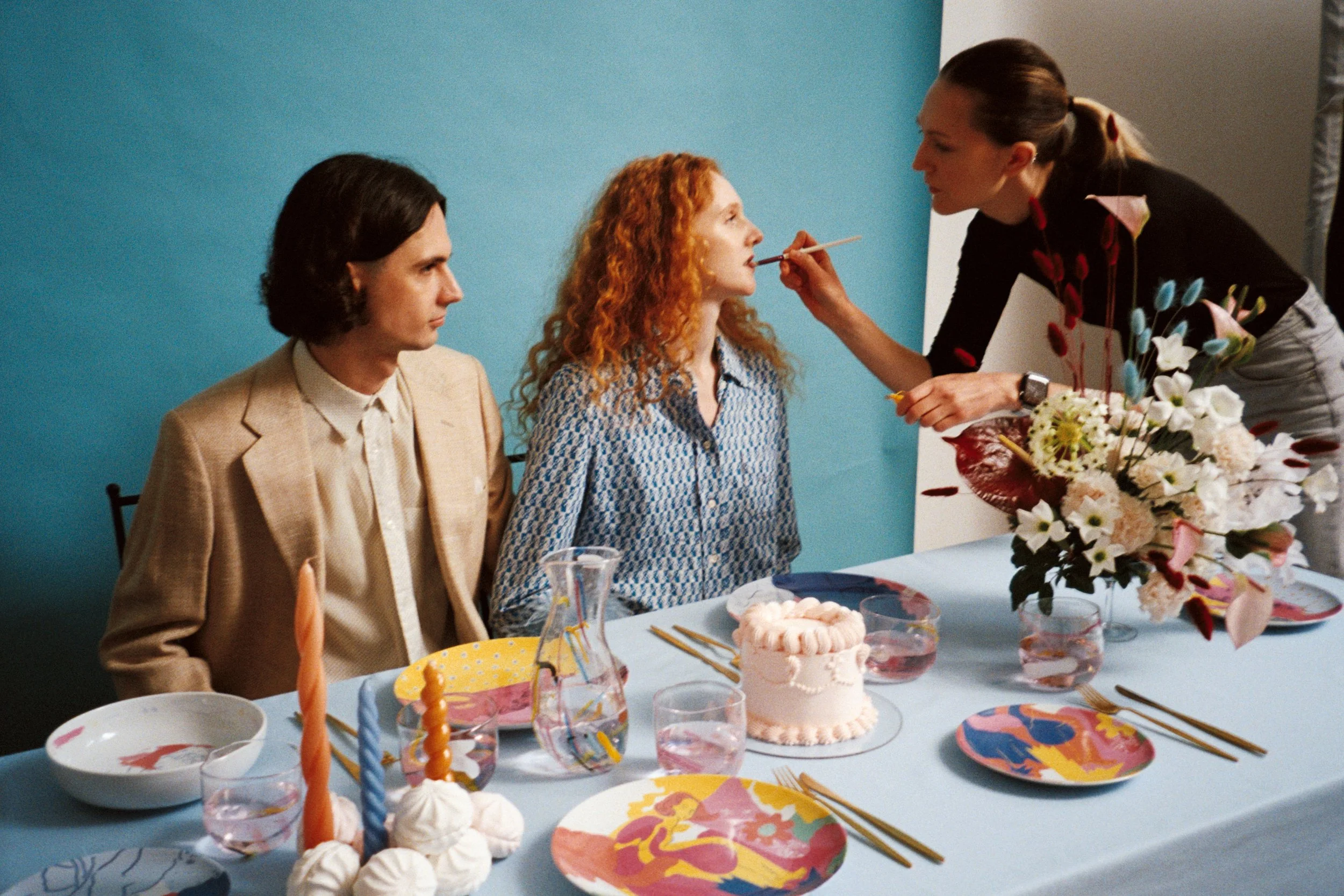 People celebrating a birthday with cake and colorful decorations at a party table.