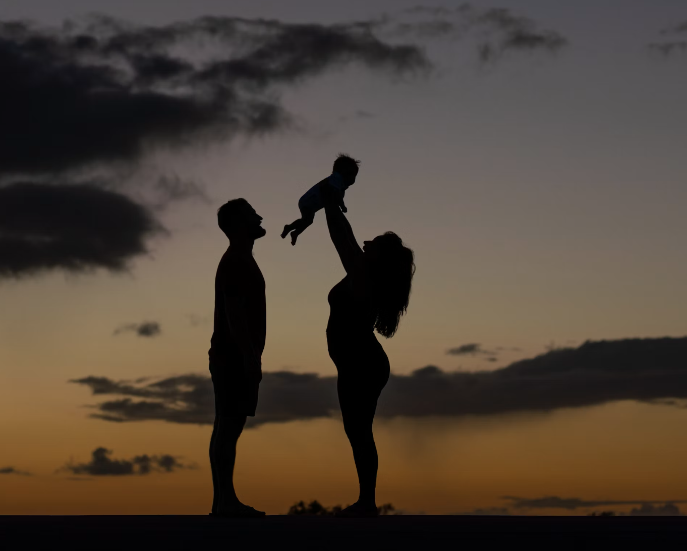 New parents holding up baby
