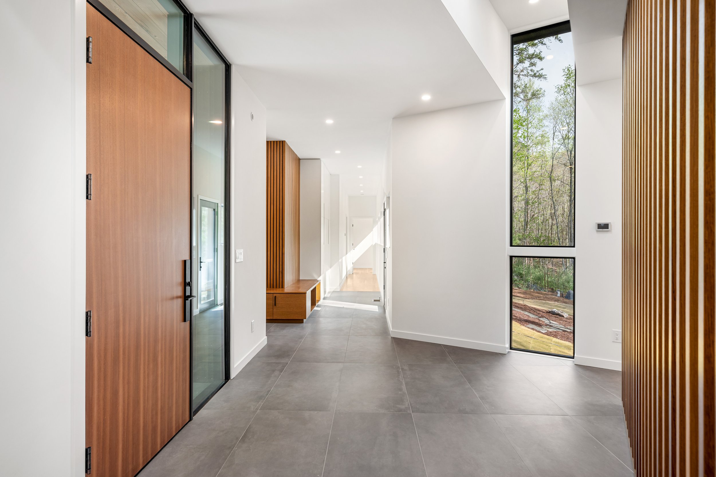  The bright foyer is a dramatic circulation hub of the house, connecting bedroom wing, garage/mudroom access, and acces to kitchen and stairs down to the gym and art studio. 
