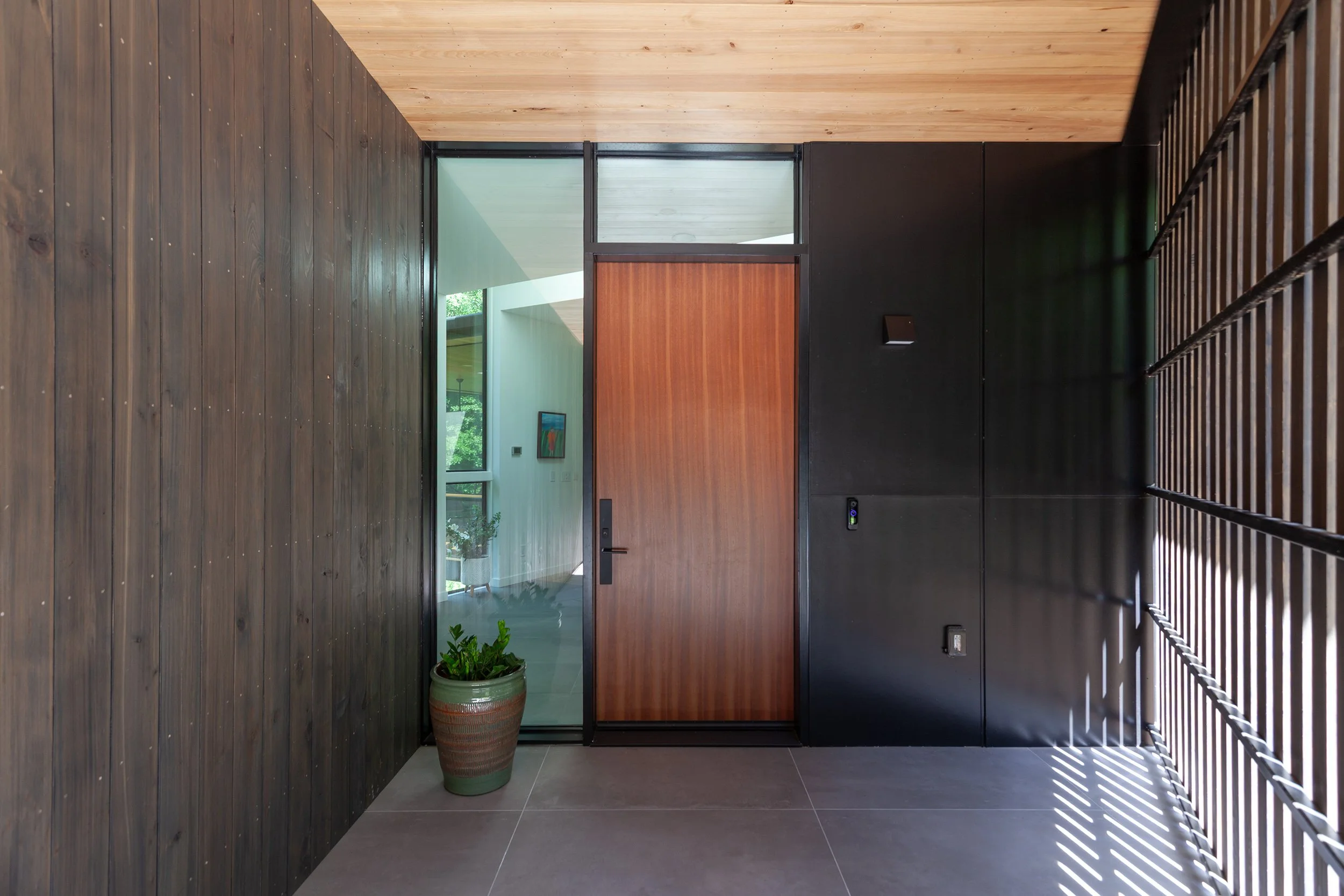  The slatted screen shelters the front porch, with large format tile flooring extending from inside to out. 