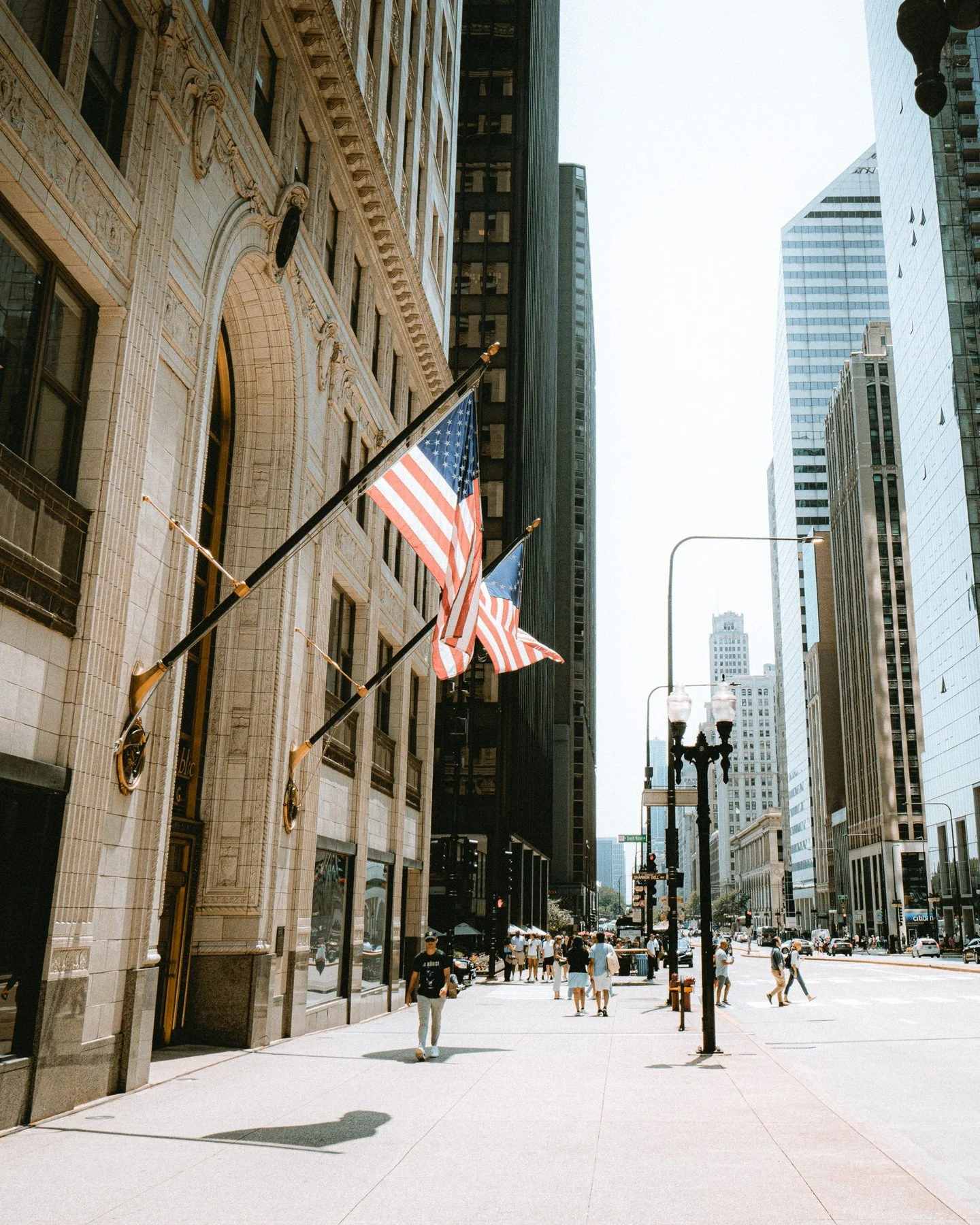 Chicago Pt:5 - Walking through downtown Chicago, every street feels alive with stories. The towering architecture draped in American flags captures the city's pride, while a saxophonist on the corner adds a soulful soundtrack to the bustling city vib