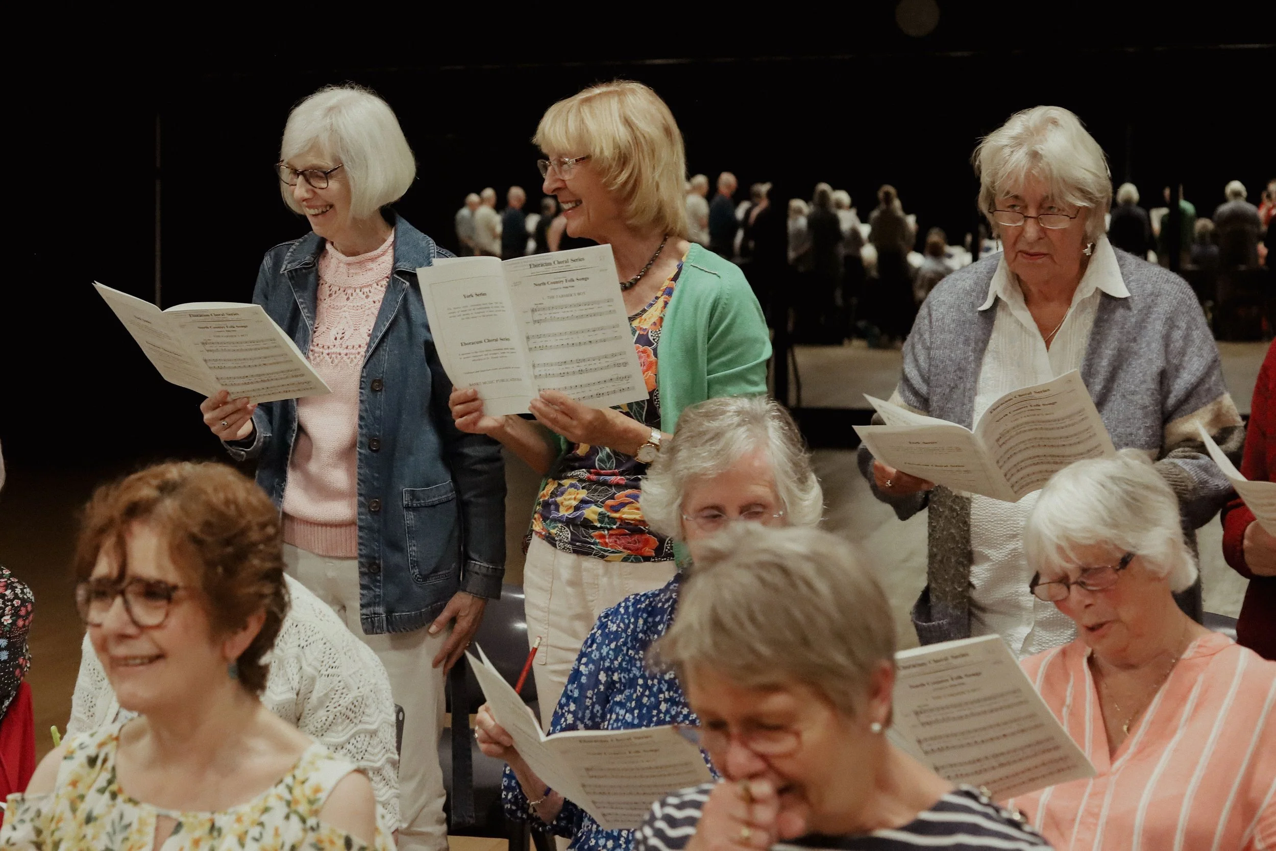Two choir members smiling as they prepare to sing