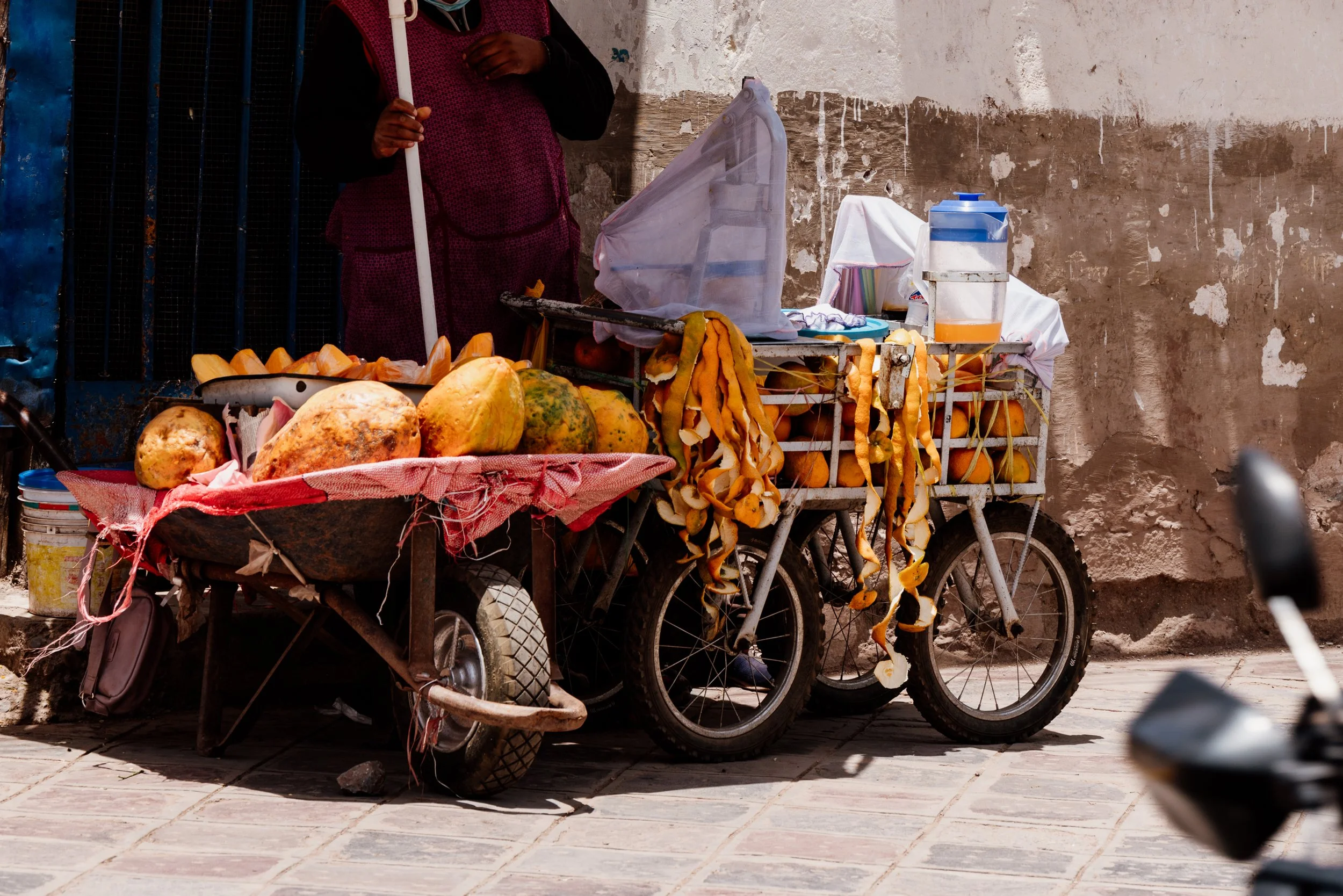 Street vendor cart with papayas and colorful containers.