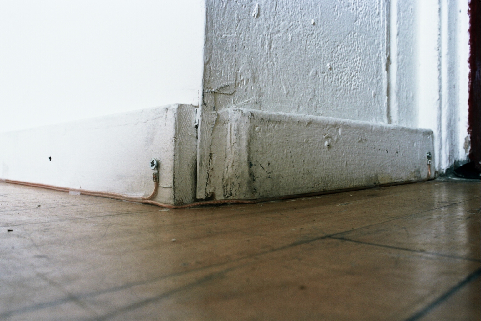 Speaker wire was laid in the perimeter of the room where the wall meets the floor.