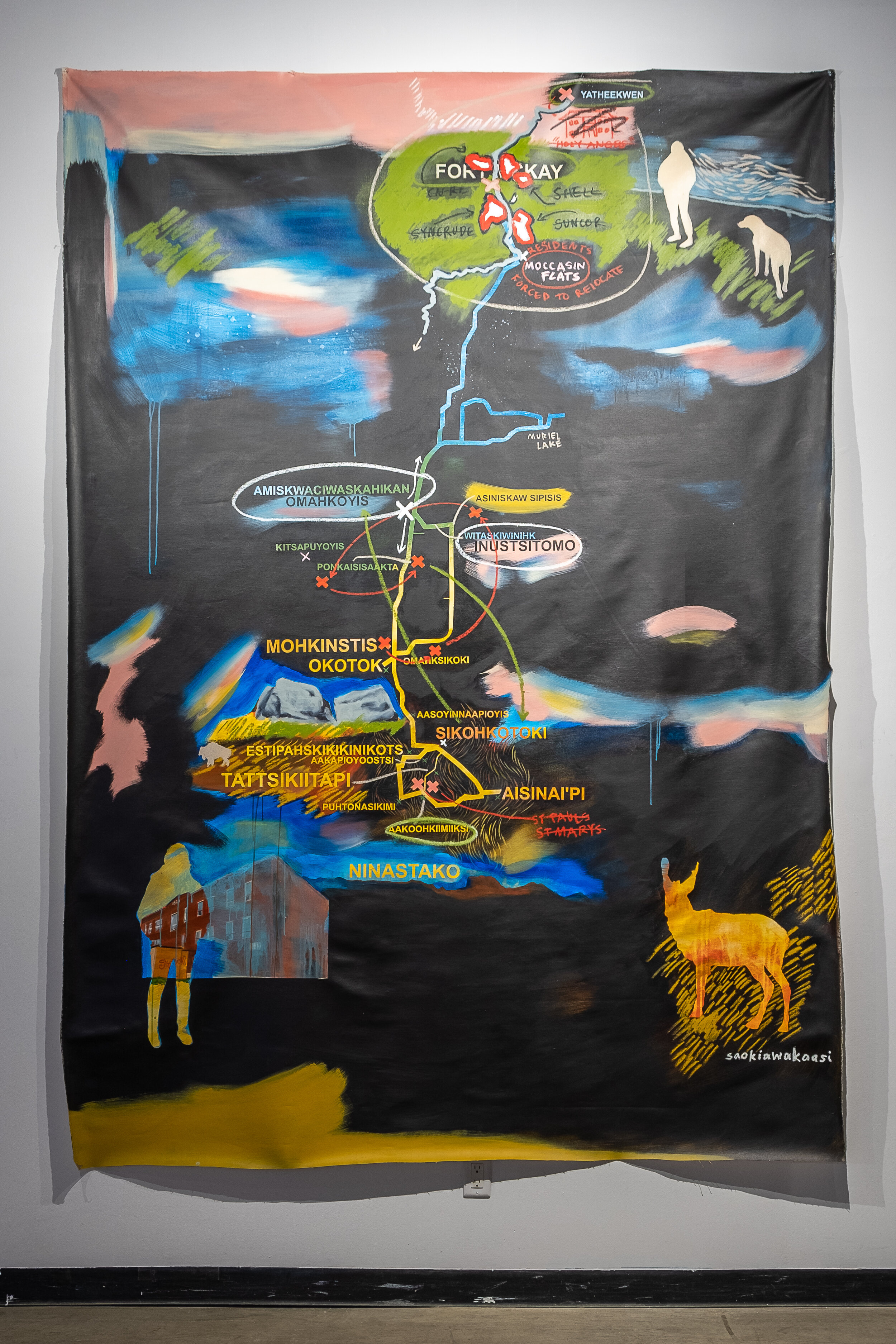  A painted map by Lauren Crazybull. The painting is mostly black, with thin yellow, and blue lines mimicking those that would be used to denote roads and rivers on traditional maps. These lines connect larger images within the map; in the top right o