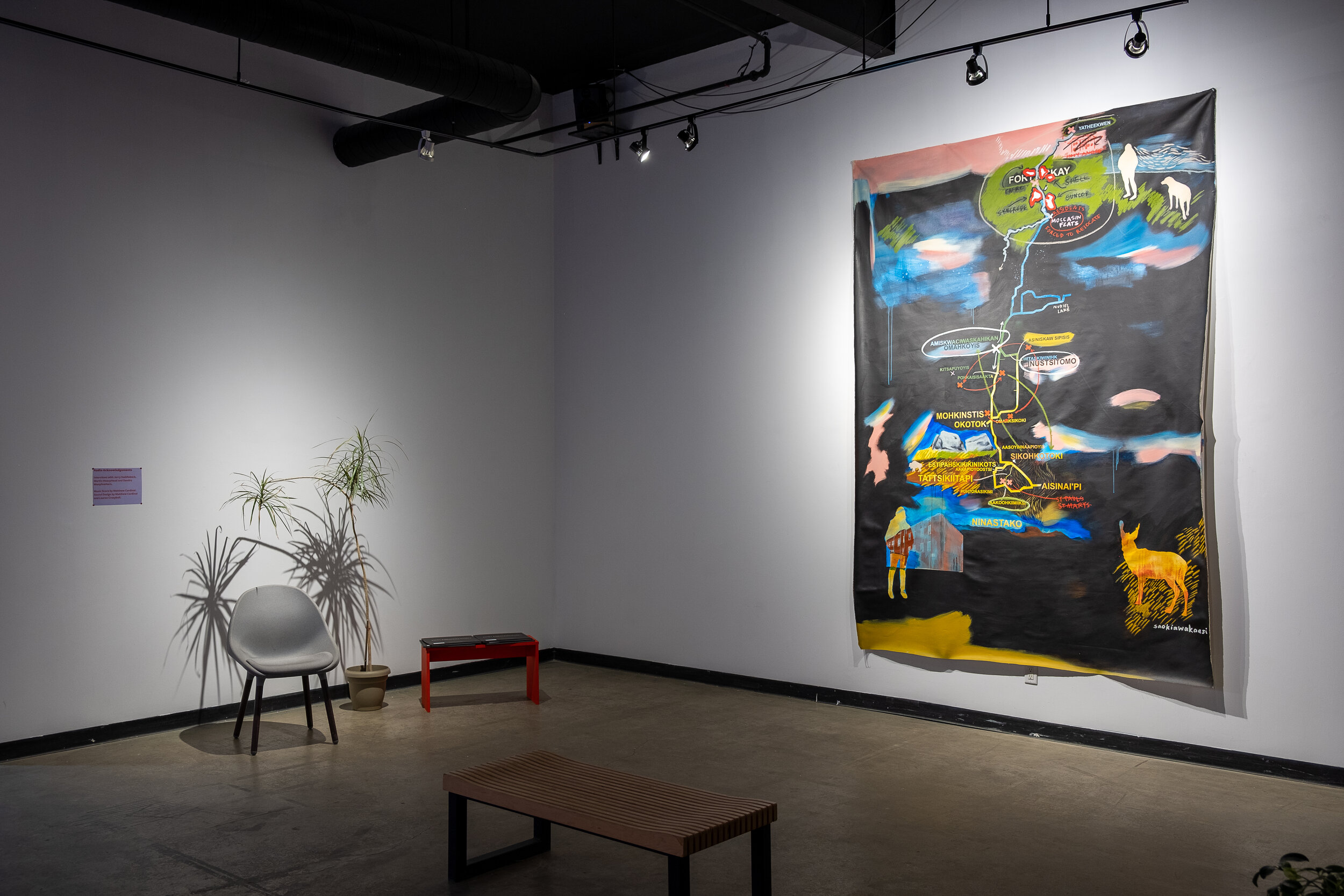  This is a wide view of the gallery, displaying Lauren Crazybull’s painted map. The map’s size can be compared to a chair sitting to the left of it - Crazybull’s map is about the height of three to four folding chairs stacked end to end, and as wide 