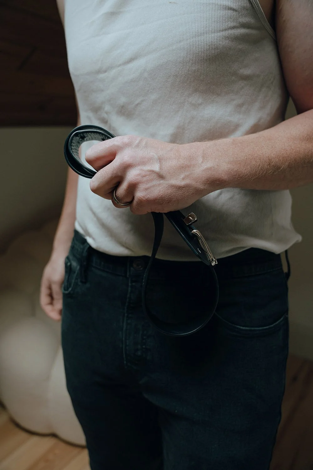A man holding a belt after taking it off, posing for an erotic photoshoot in Hamilton, Ontario
