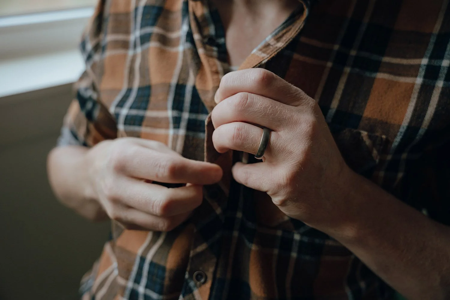 A man unbuttoning his flannel shirt at an erotic photoshoot in Hamilton, Ontario