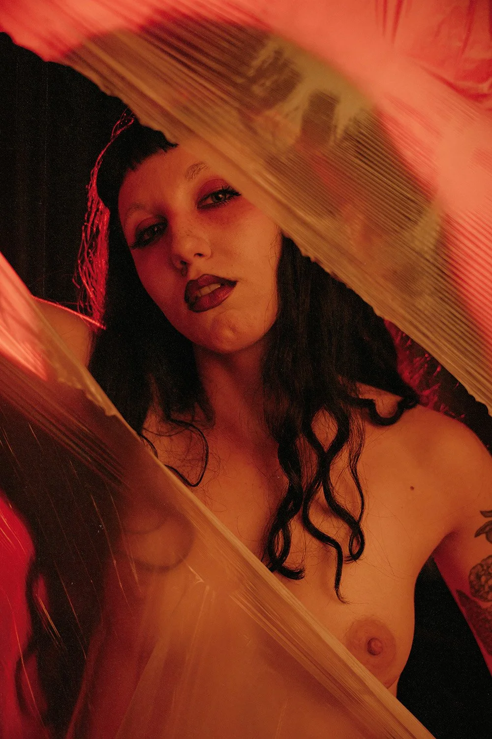 Woman ripping through a sheet of plastic to reveal herself, shot at a creative boudoir shoot in Toronto, ON