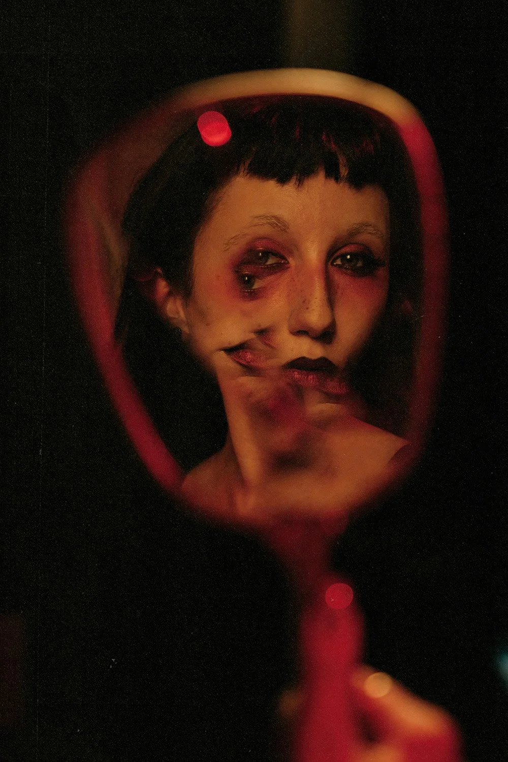 Woman looking at her distorted reflection in a broken mirror at a creative boudoir shoot in Toronto, Ontario.
