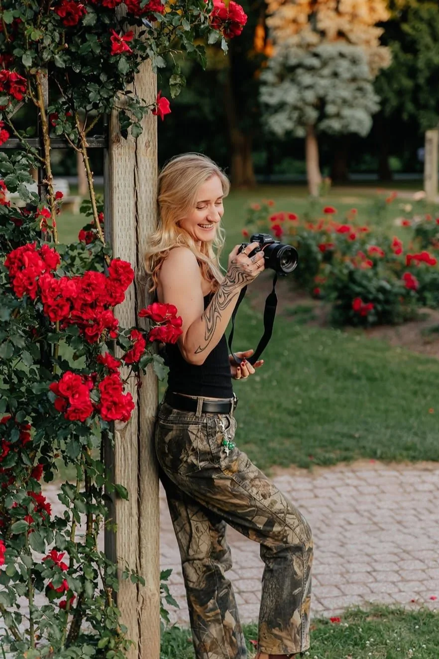 Irene, the boudoir photographer, smiling and holding a camera