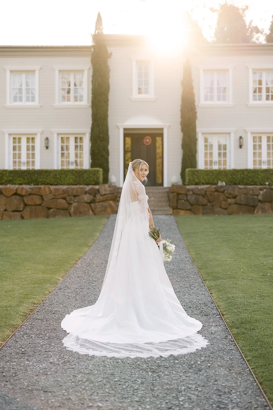 Bride smiling over her shoulder in-front of wedding venue