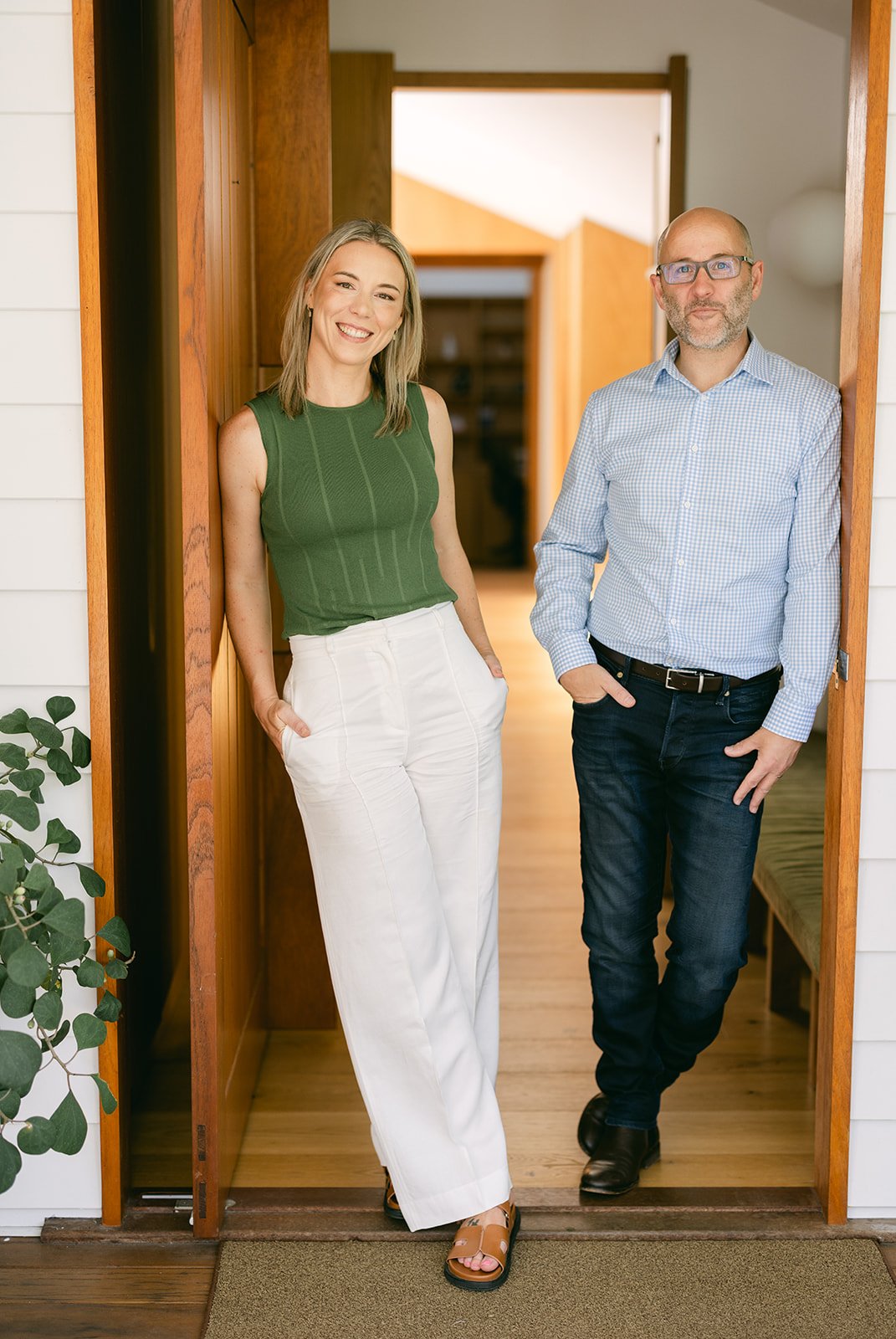 A man and woman stand on opposite sides of the door posing for a branding shoot