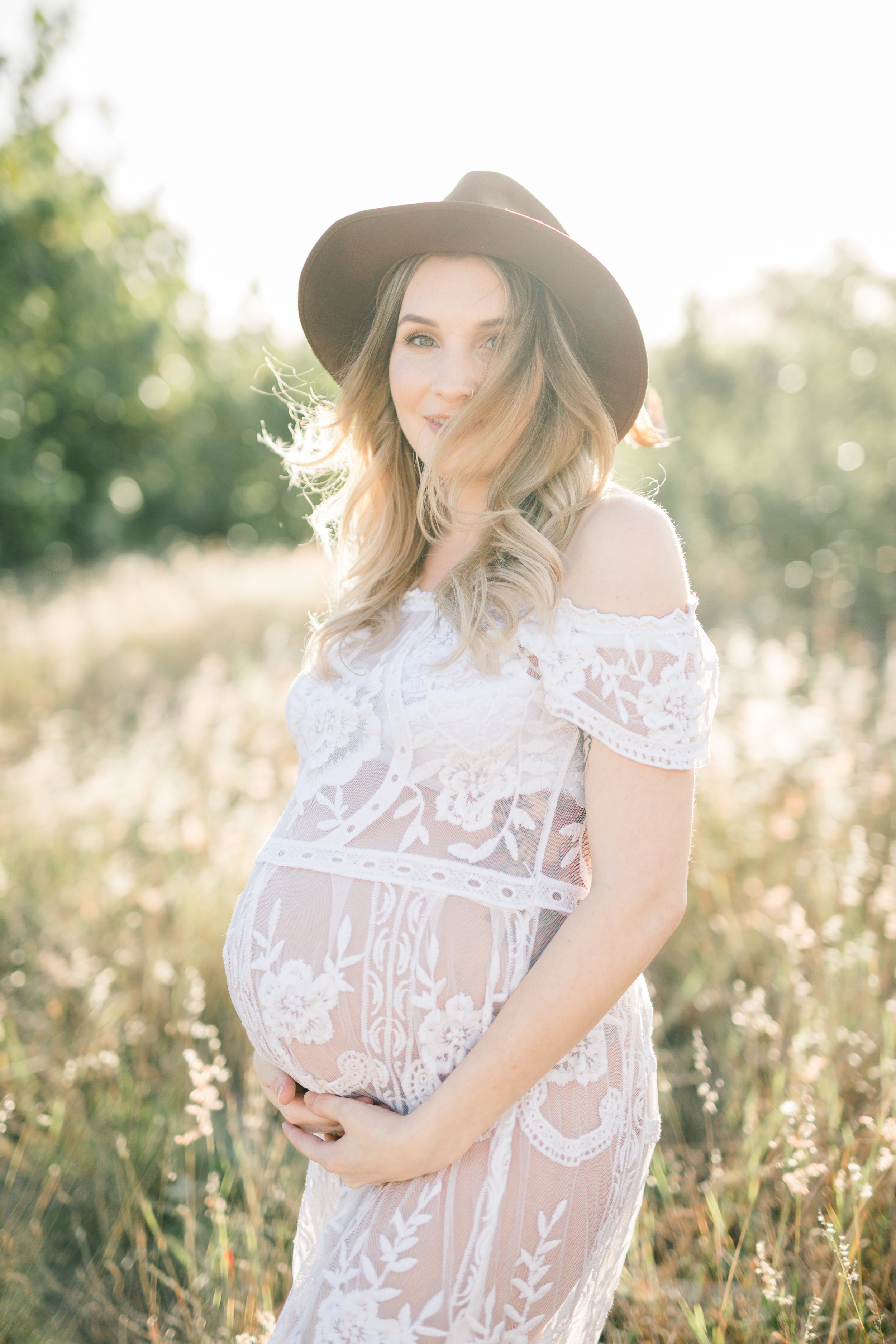 Bohemian mother in lace gown cuddling her belly