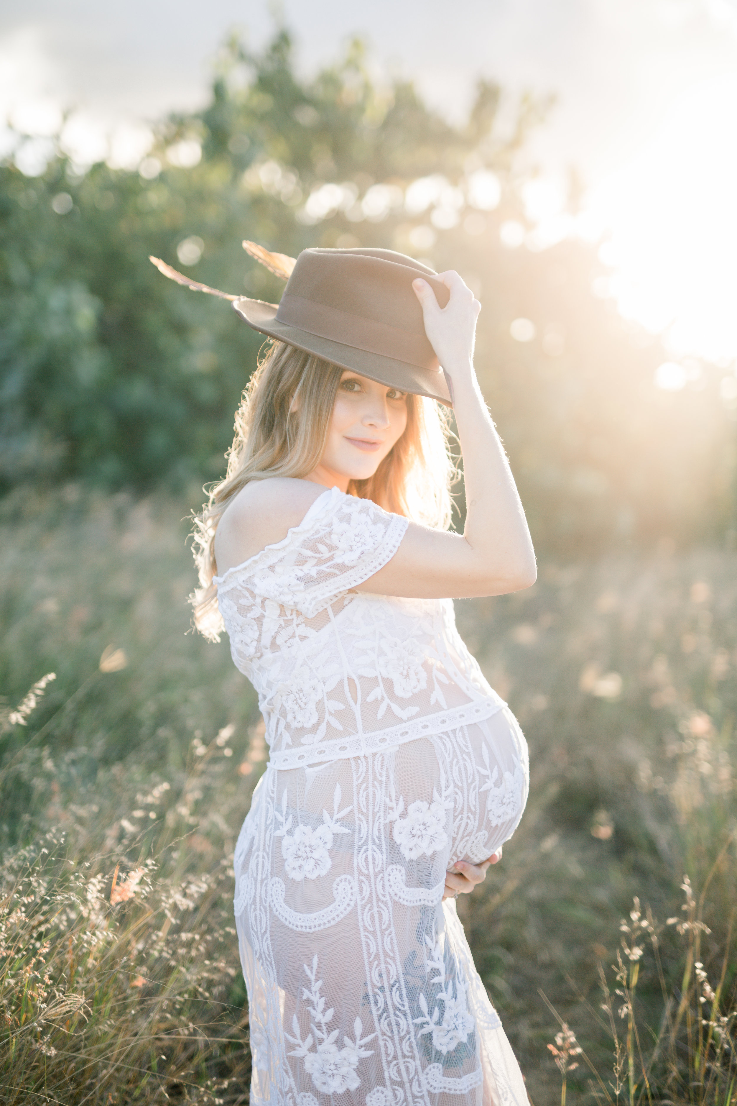 Mum to be wearing a feathered hat at sunset