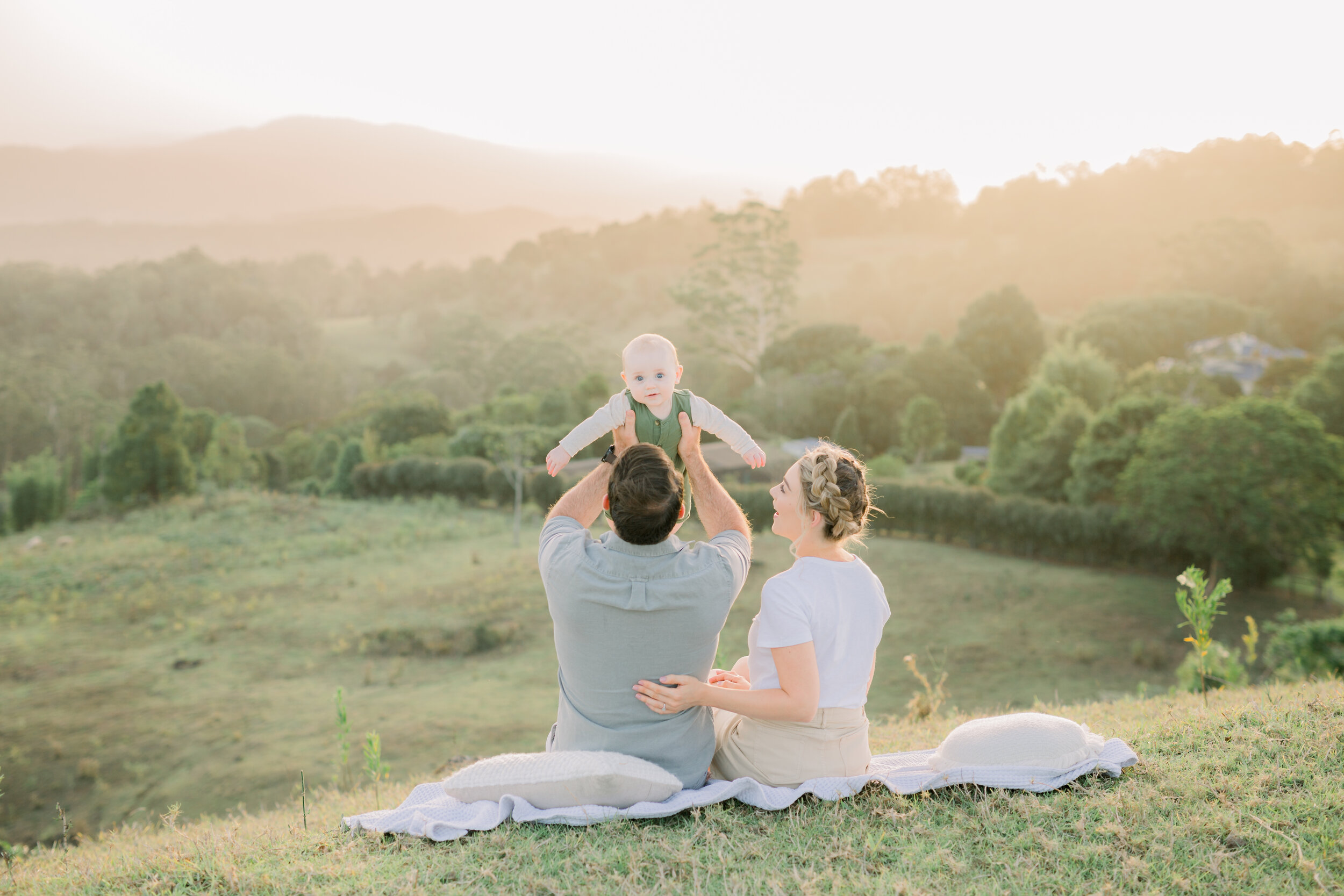 Dad holding up his baby boy overlooking Maleny mountaintops