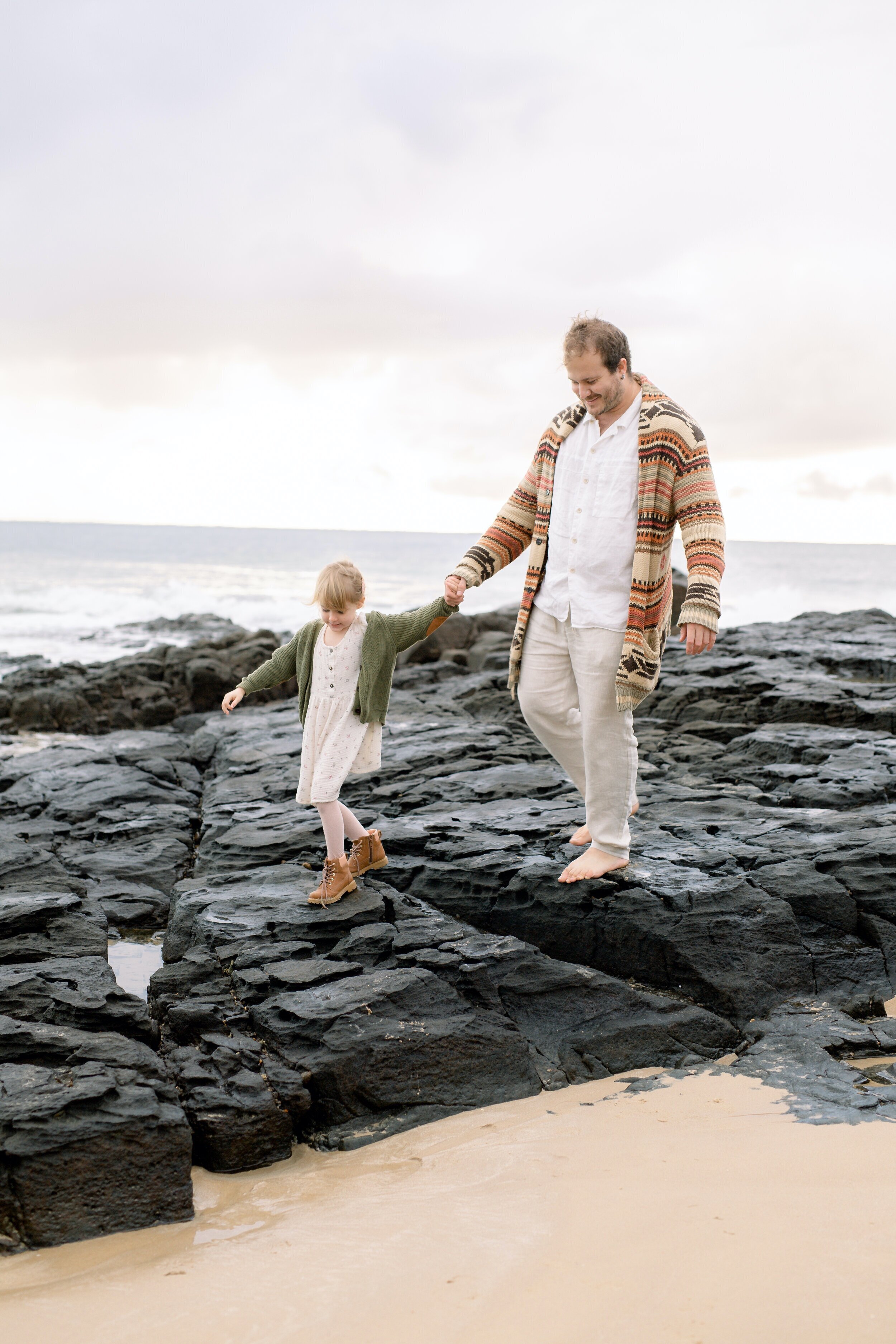 Father holding his daughters hand at the beach