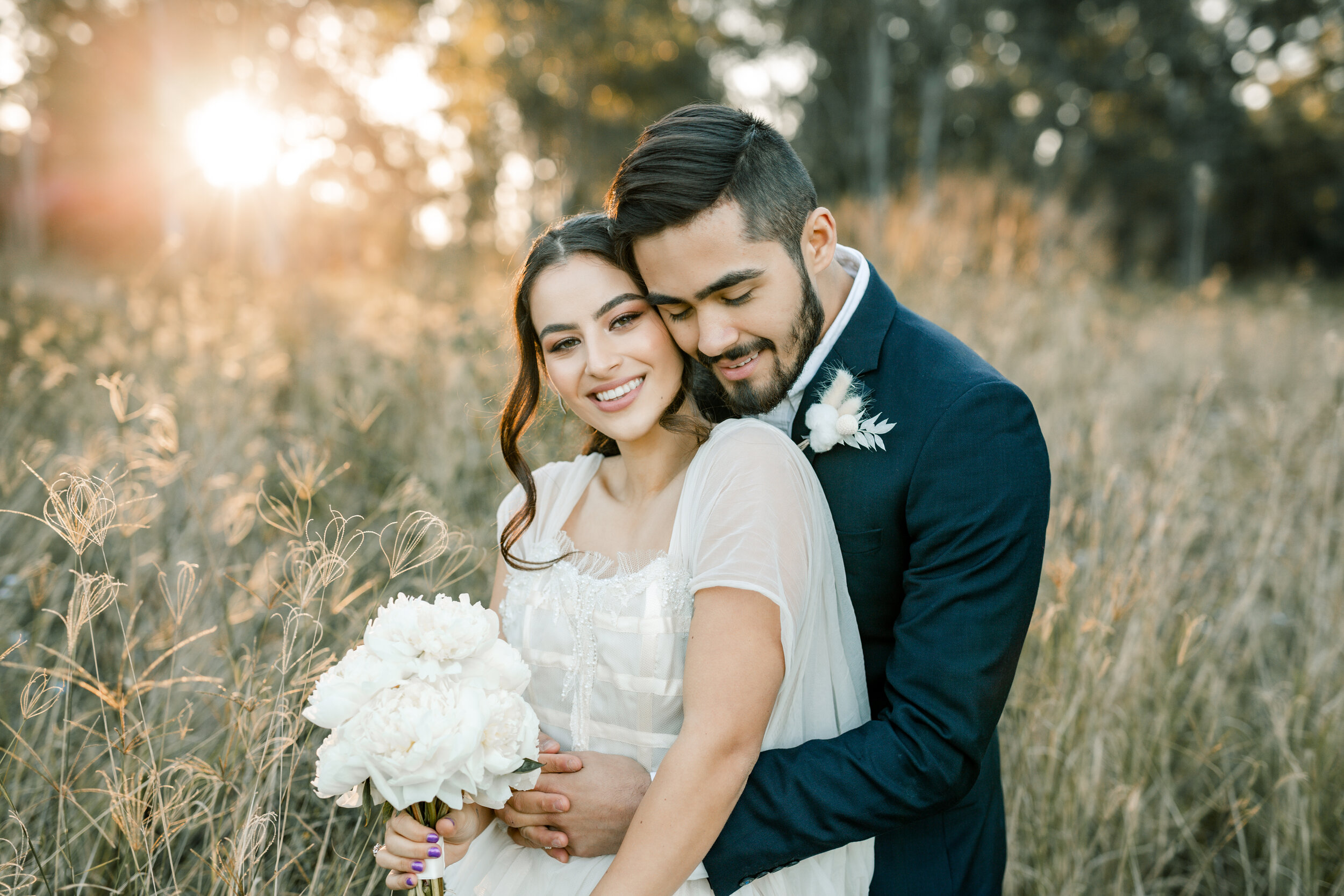 Wedding couple portrait in a grassy field at sunset