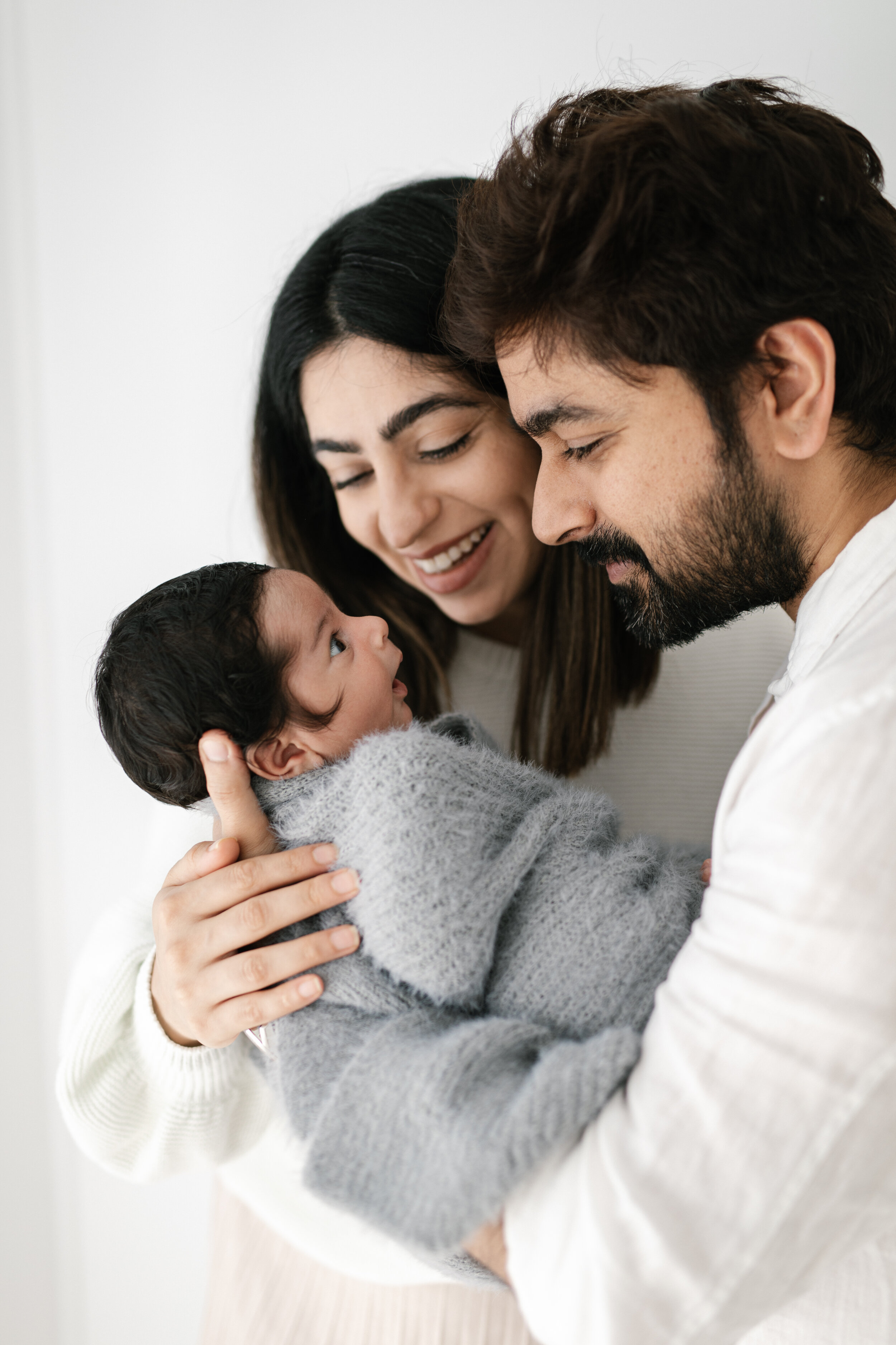 Newborn baby boy cuddled up with mum and dad