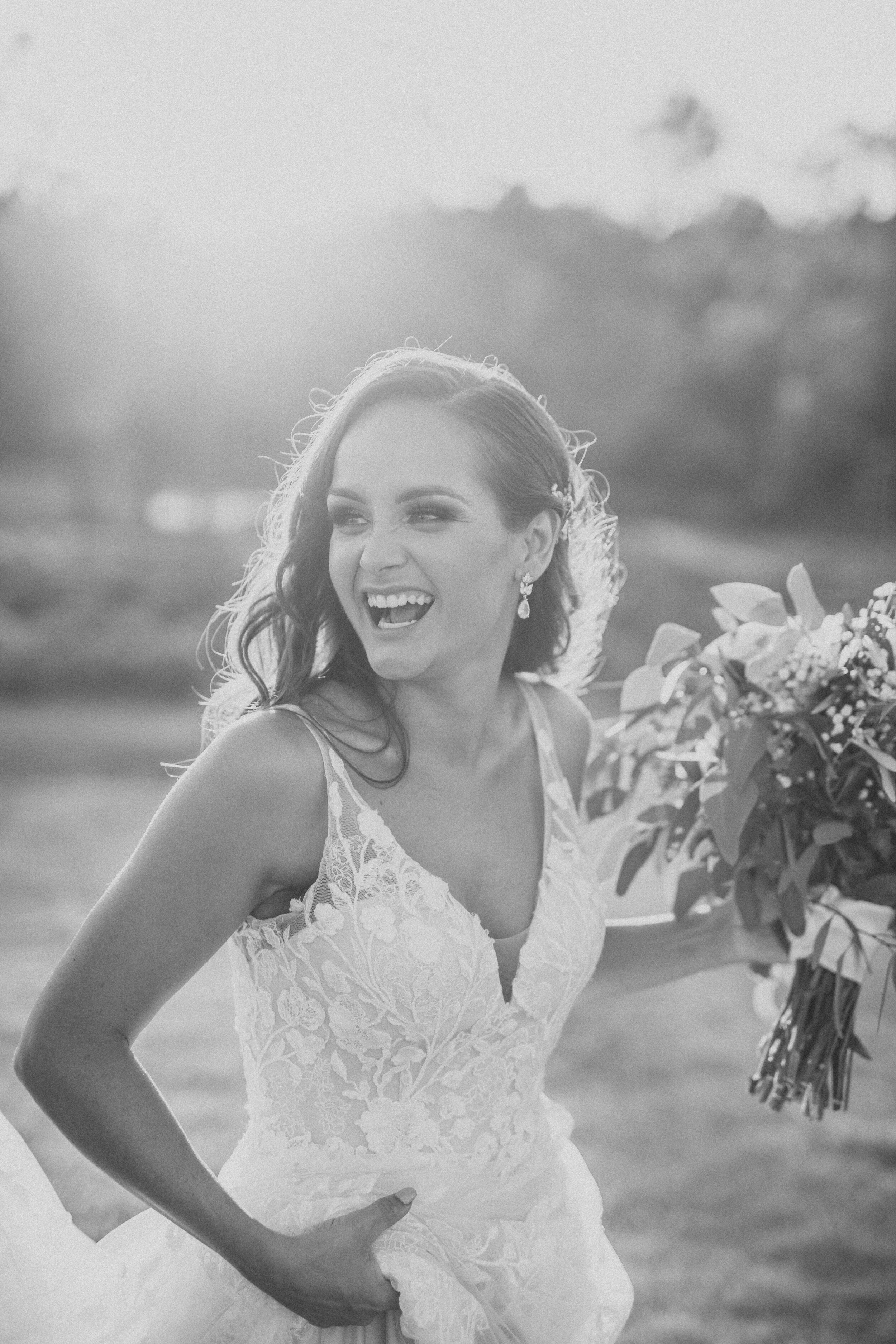 Black and white photograph of a bride laughing holding her bouquet