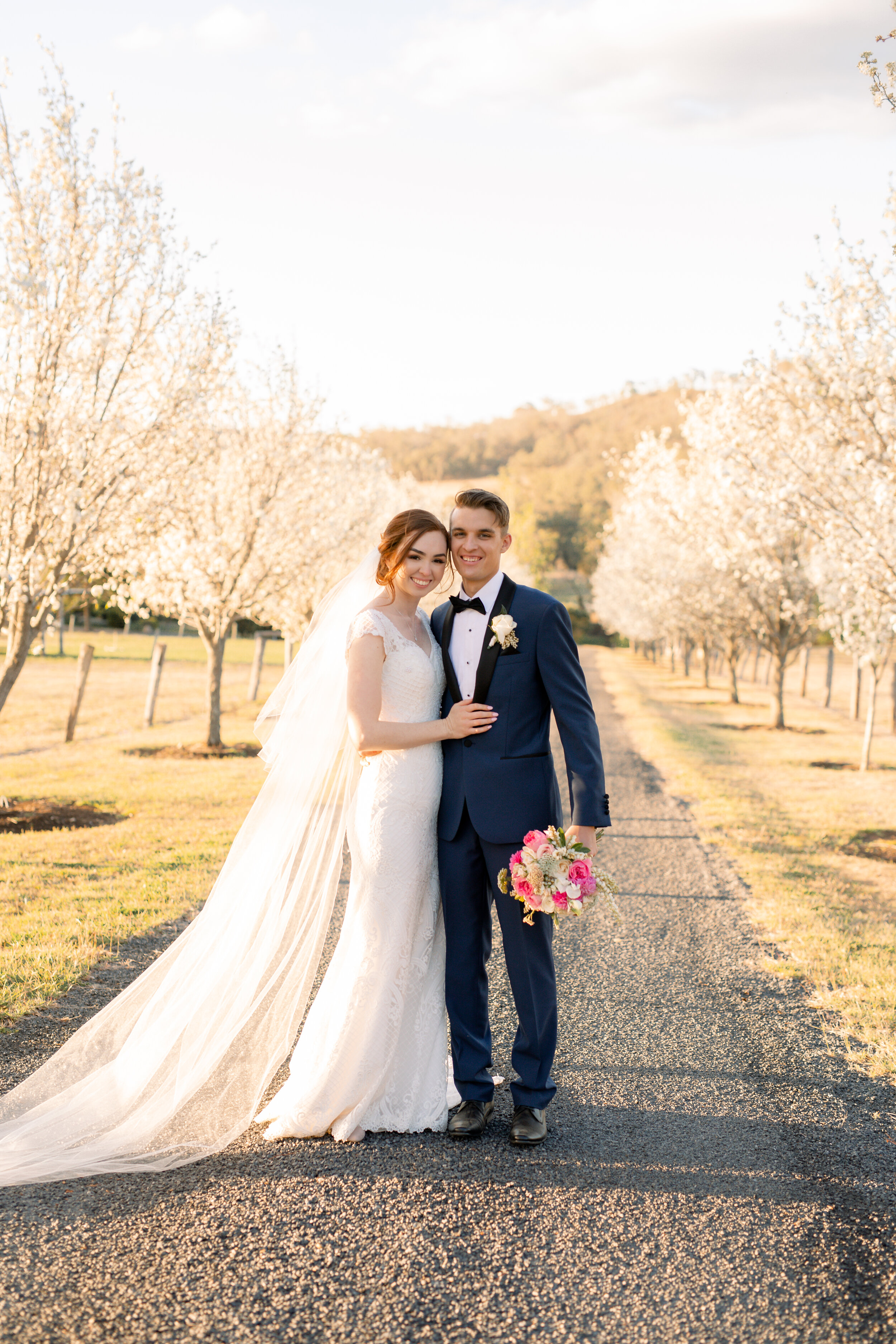 Bride and groom surrounded by white floral blooming trees