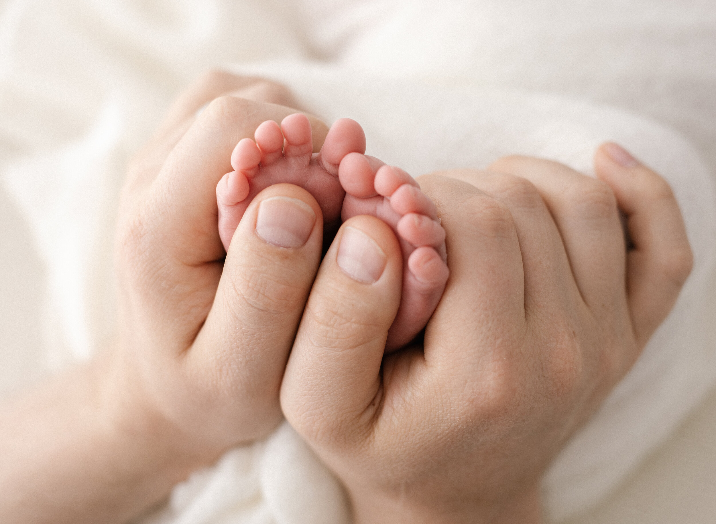 Dads hands holding his newborn babies tiny feet