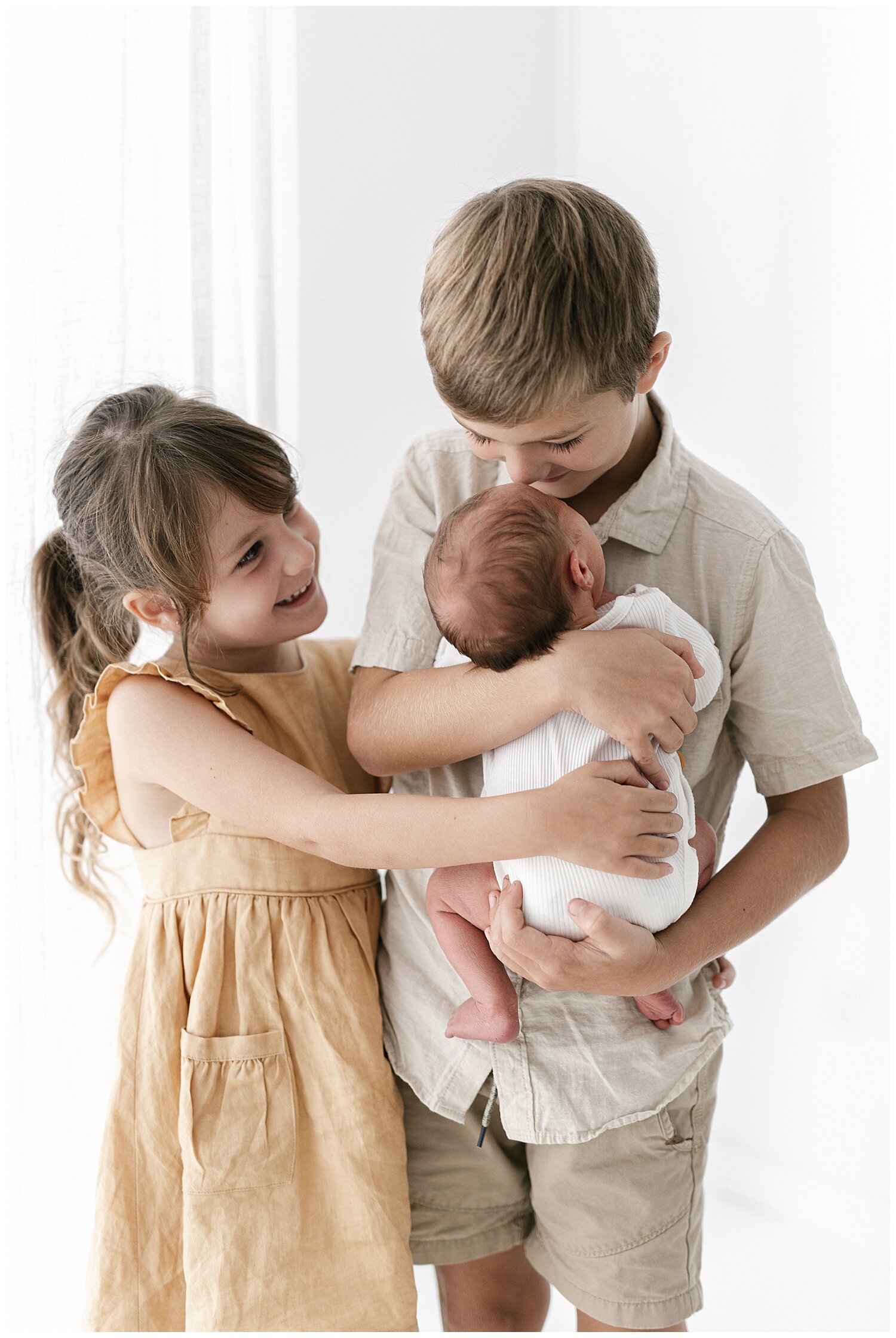 loving older brother and sister cuddling their newborn baby brother in brisbane photography studio