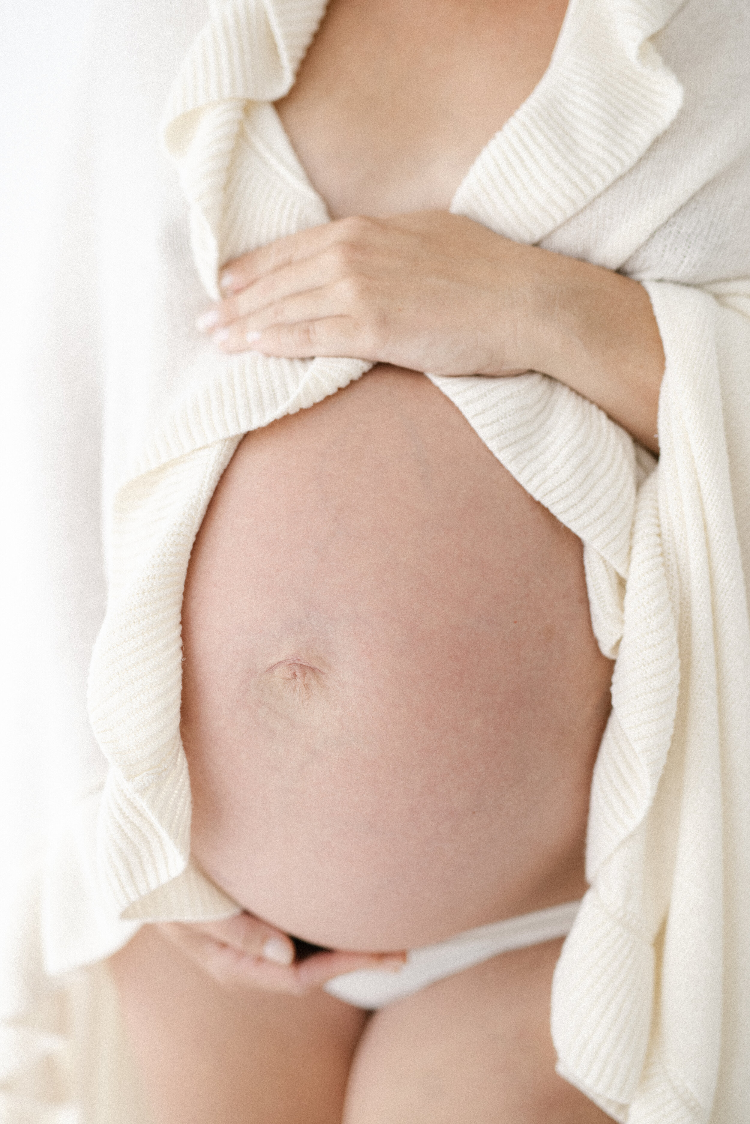 maternity photograph of baby bump covered in a white blanket