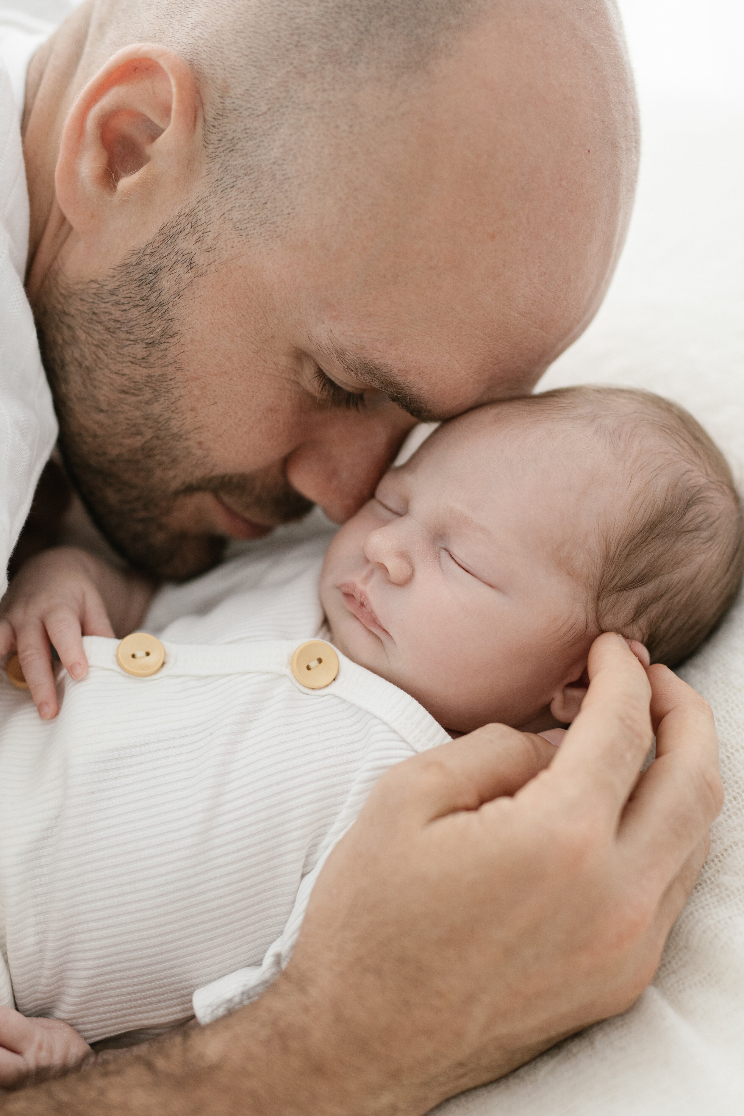 dad snuggled in to his newborn baby photographed in a brisbane newborn studio