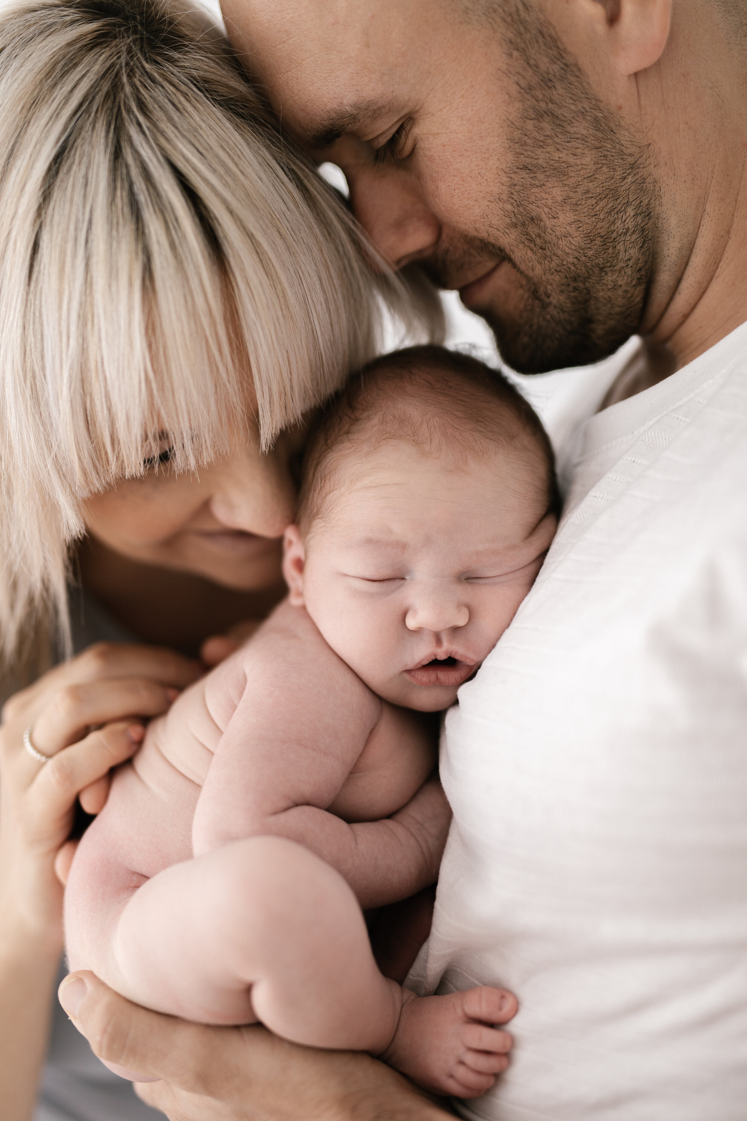 Newborn baby snuggled into mum and dad