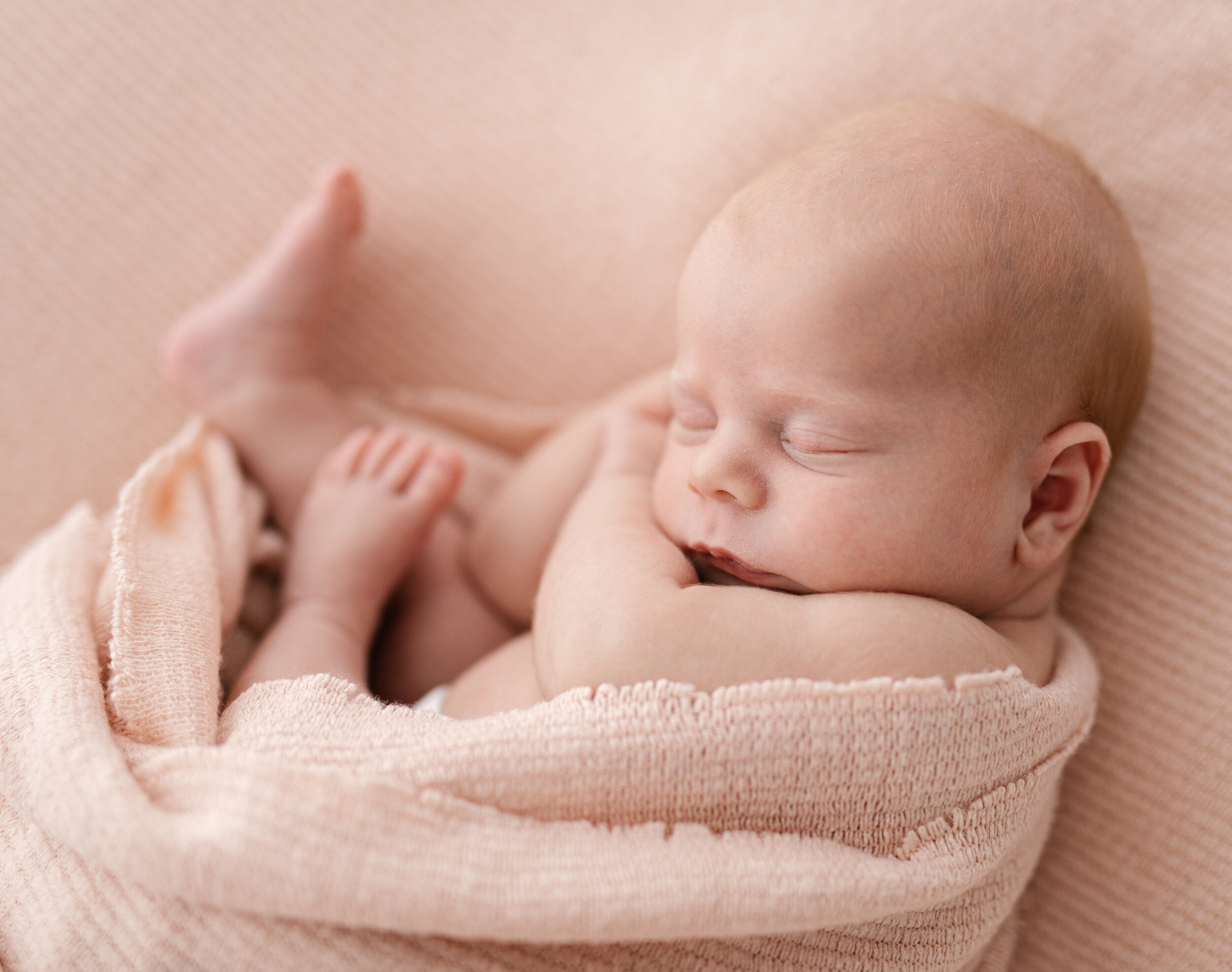 Brisbane newborn baby photographed cuddled in a soft pink blanket 