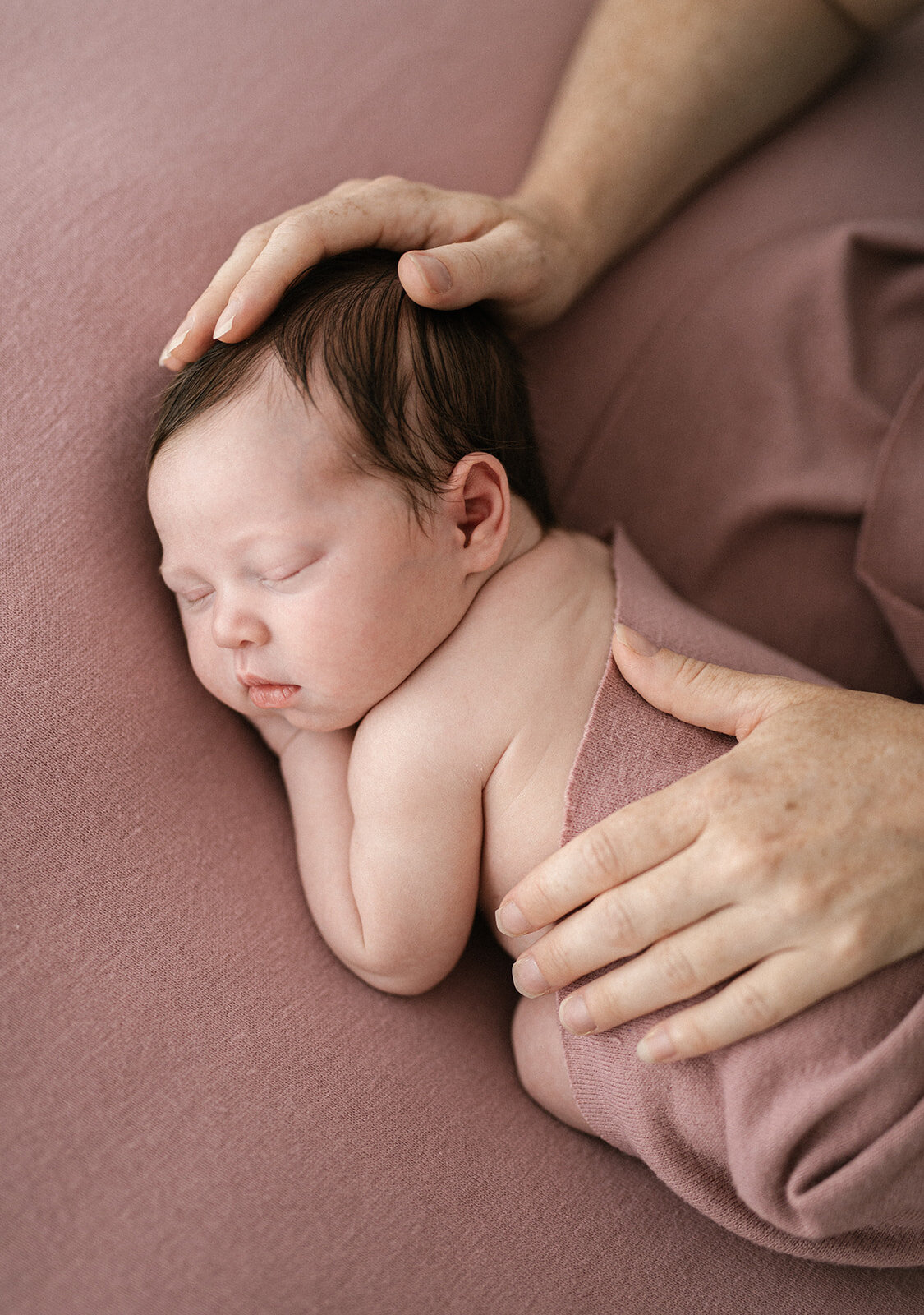 newborn baby girl being held with her mums hands