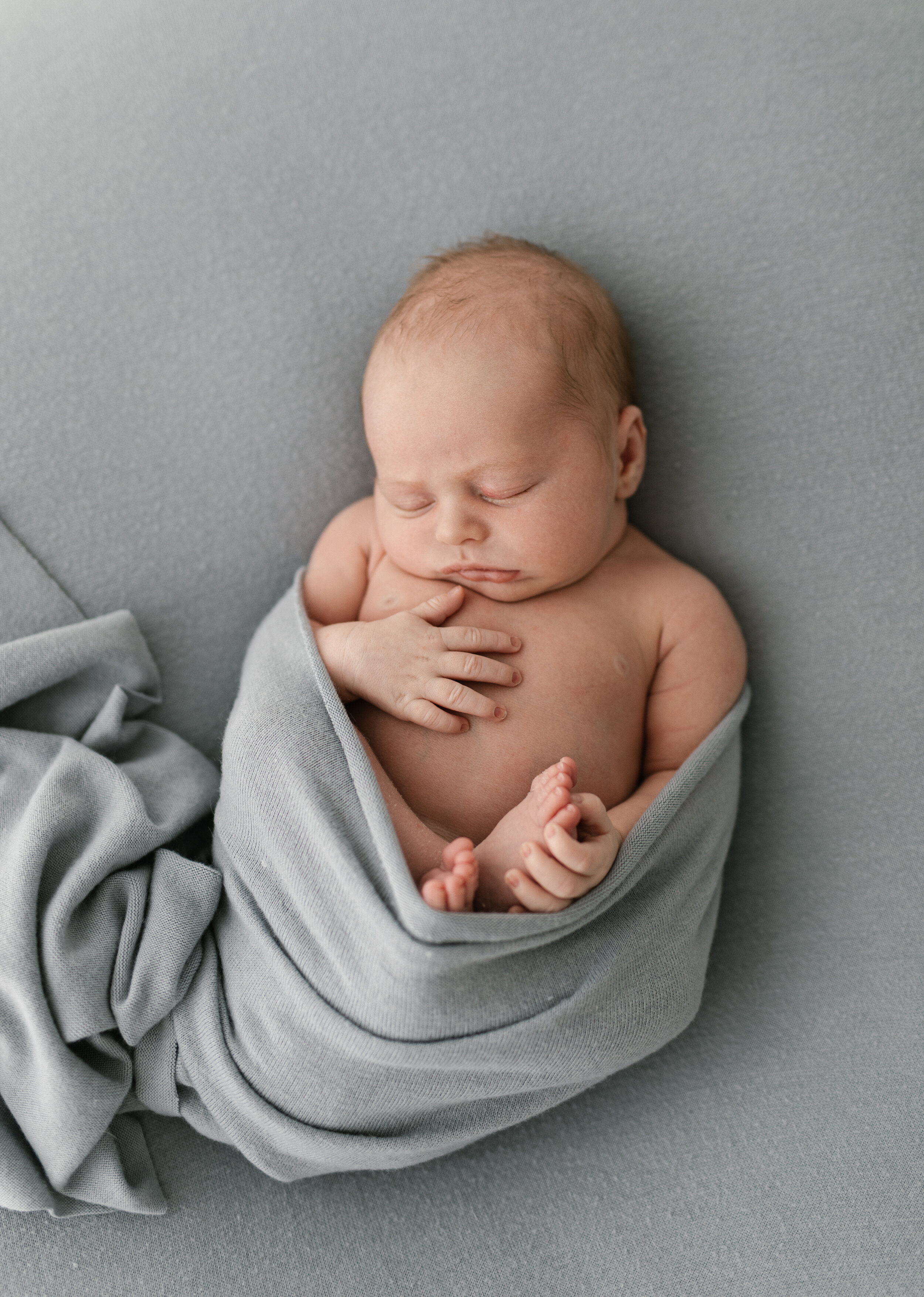 newborn baby wrapped in a soft blue wrap