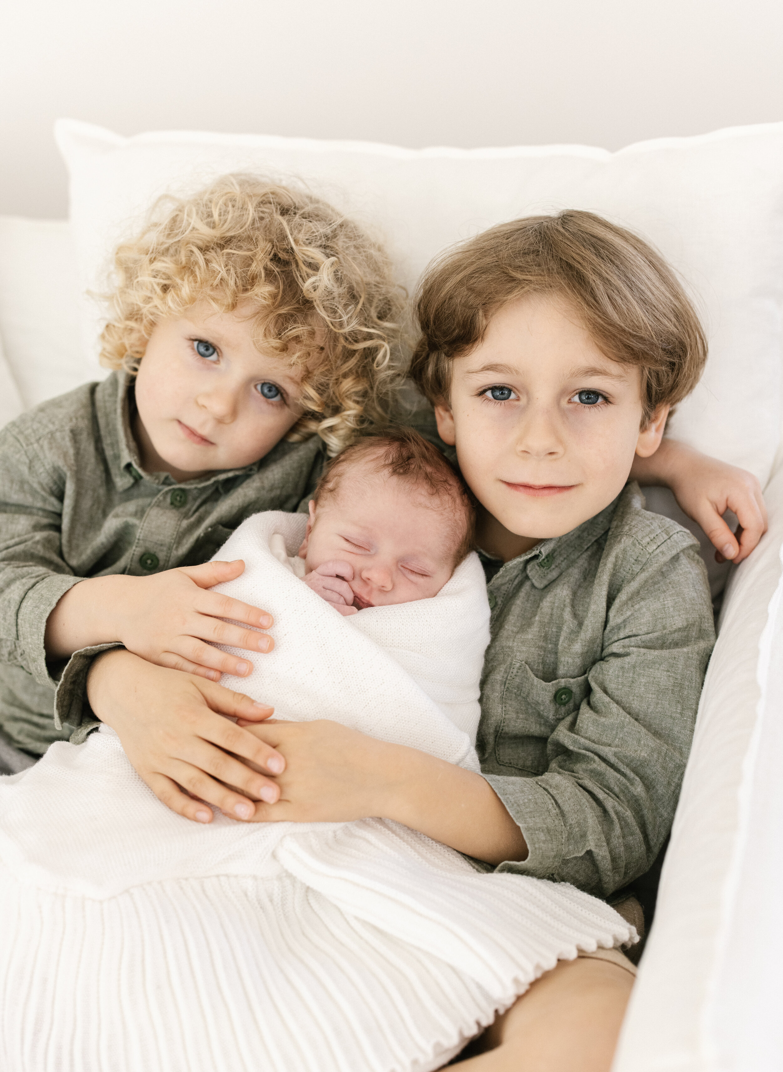 older brothers cuddling their newborn baby sister