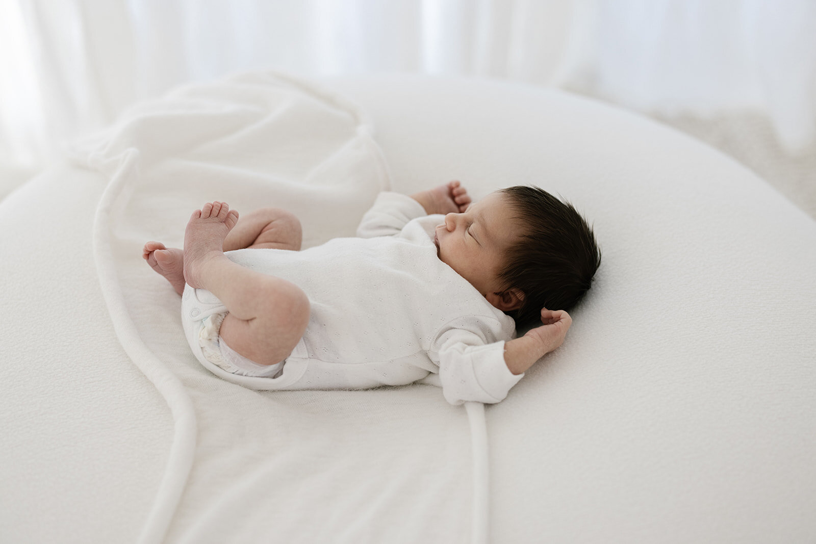 Newborn sleeping on a white blanket