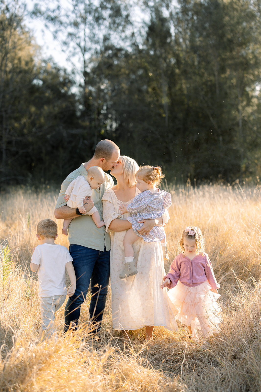Mum and Dad kissing in the golden grass surrounded by four children