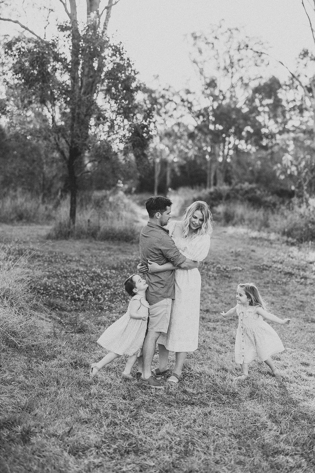 Twin sisters running aorund their mum and dad in a field