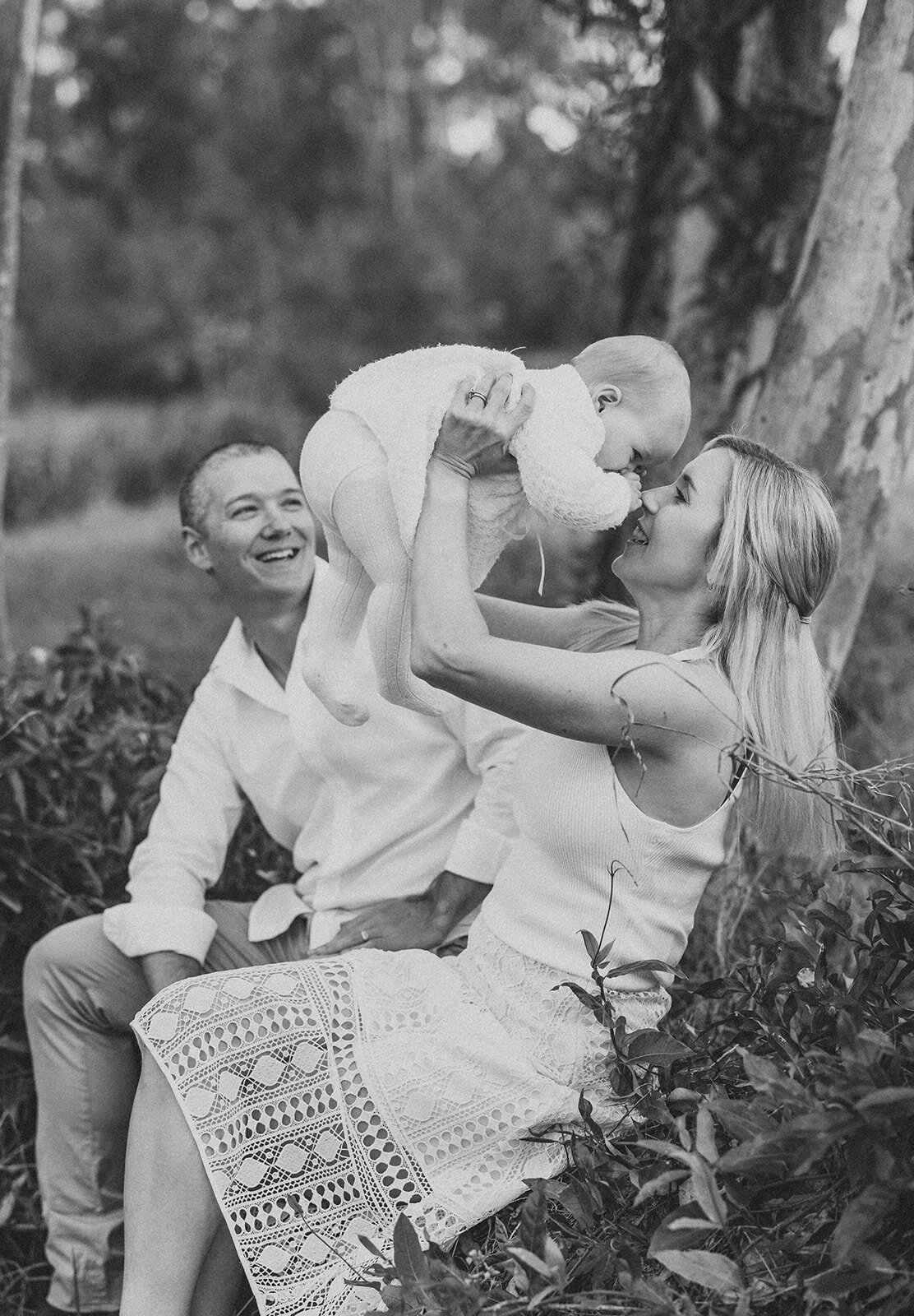 Mother holding her baby girl in the air and Dad smiling at them both