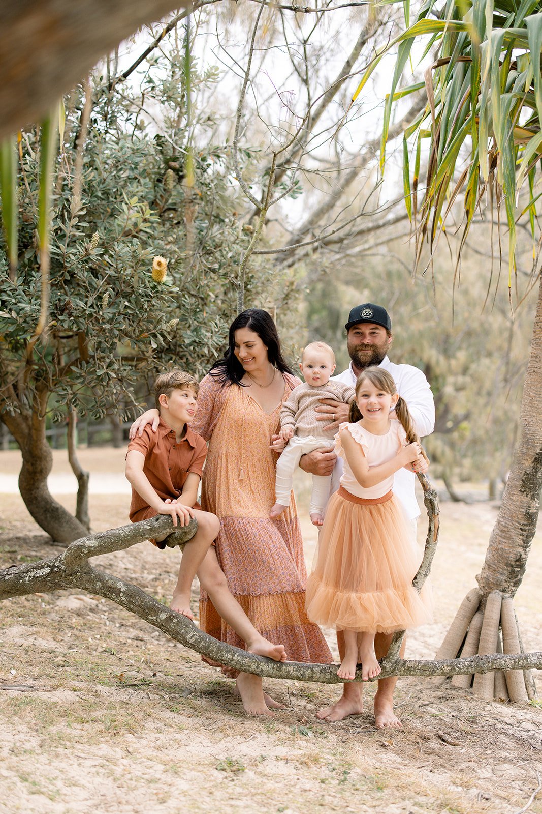 Family smiling together amongst the trees at Noosa beach