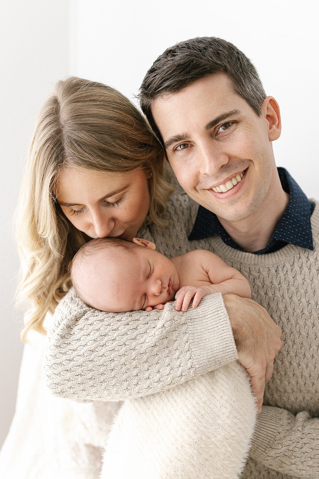 A mother and father love on their newborn baby in a brisbane photography studio