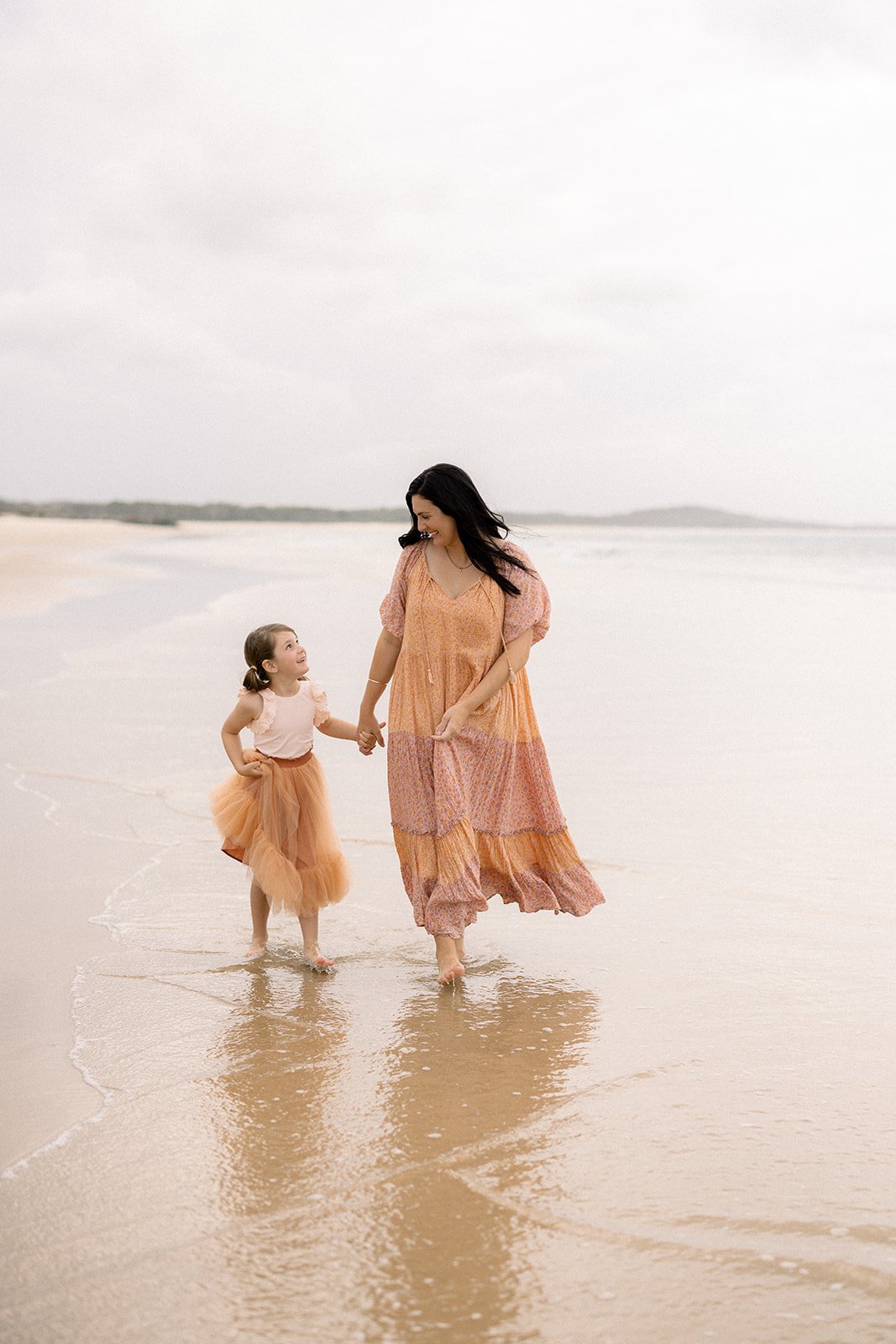 Mother and daughter holding hands on a Noosa beach
